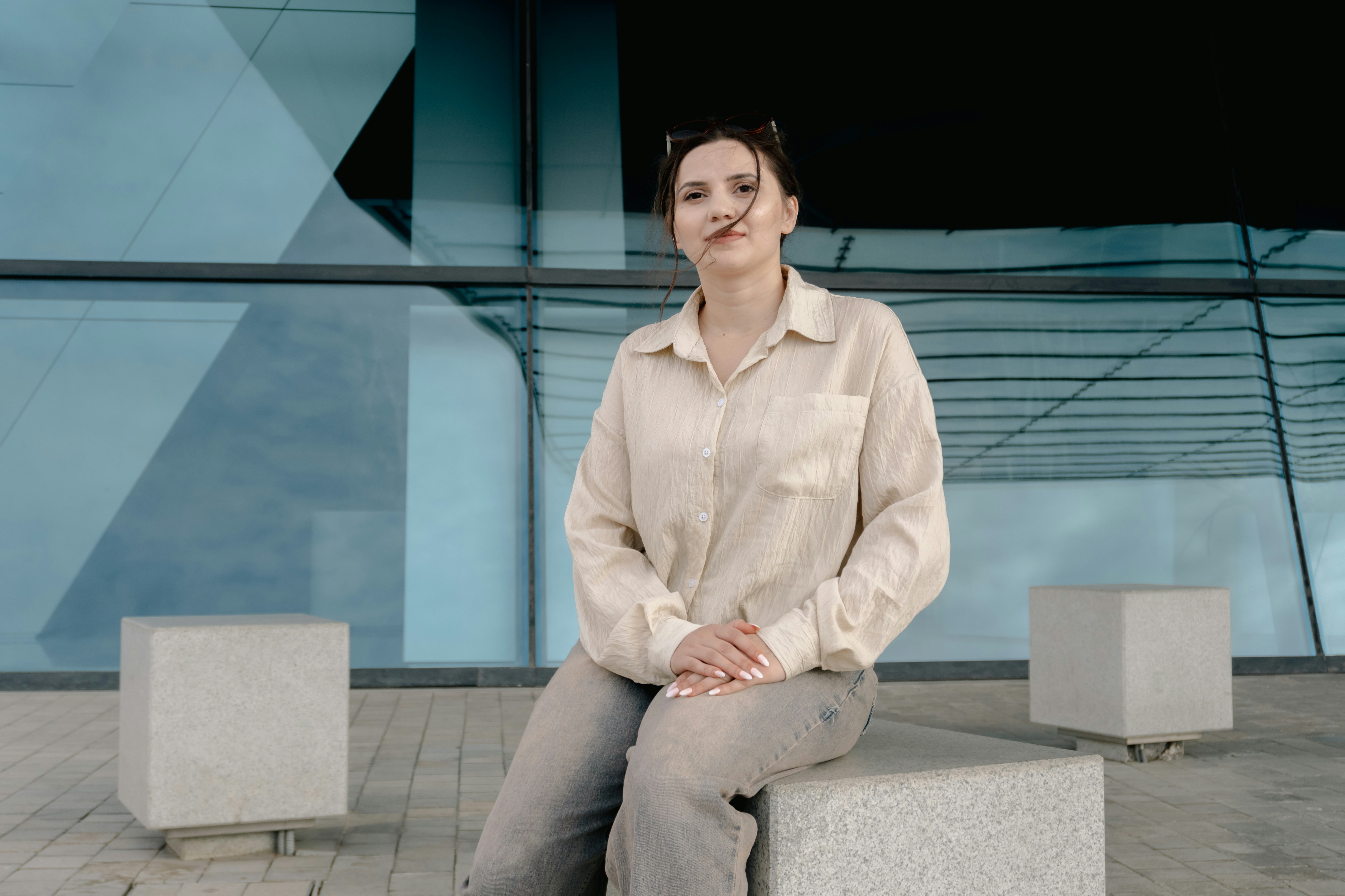 A woman sitting on a stone block by a blue building