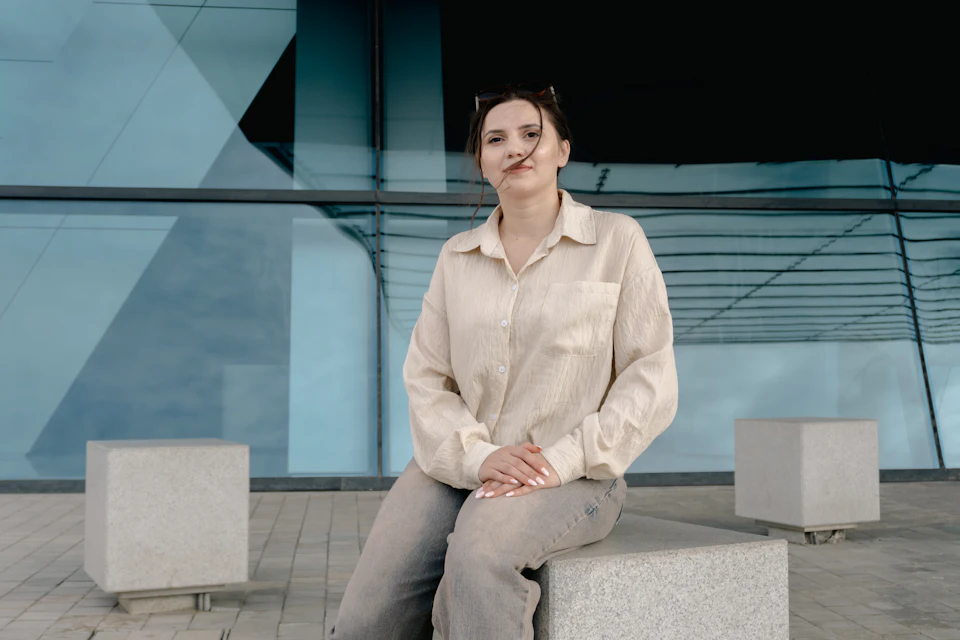 A woman sitting on a stone block by a blue building