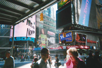 People walk amidst bright billboards in bustling times square.