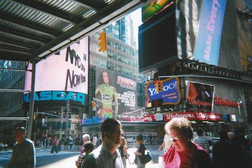 People walk amidst bright billboards in bustling times square.