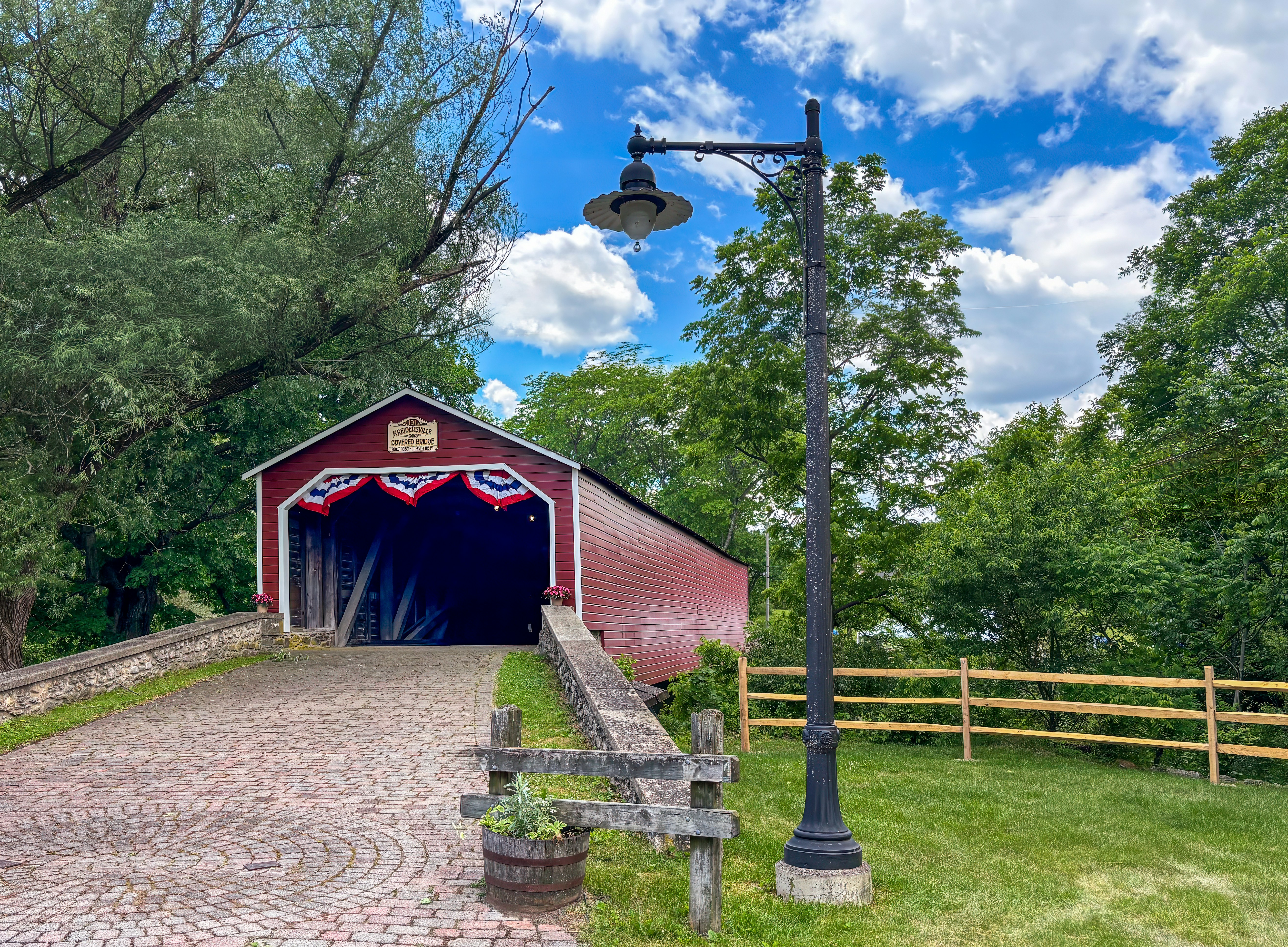 A red covered bridge with patriotic bunting and a lamppost.