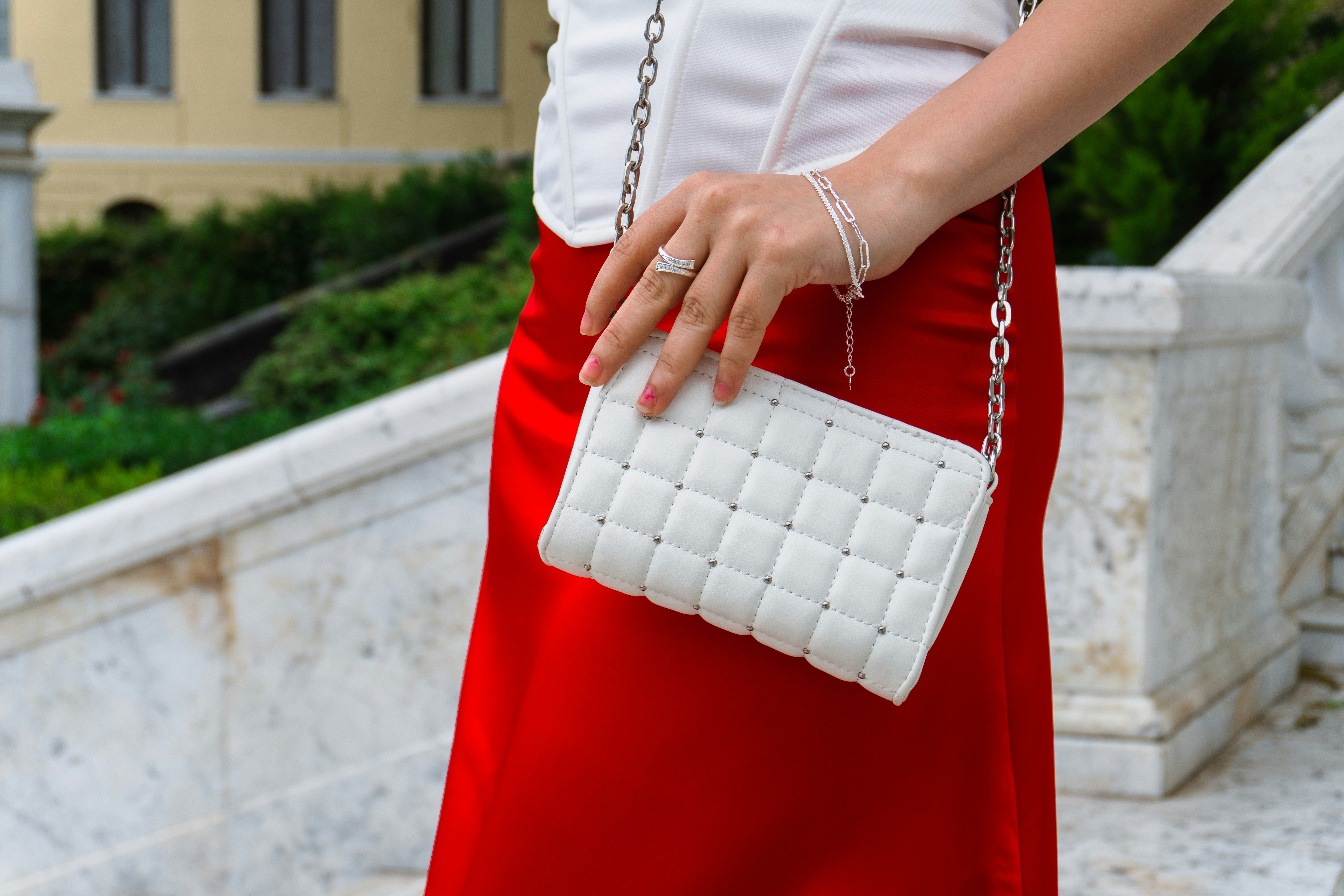 Fashionable woman holding white quilted bag on a staircase.