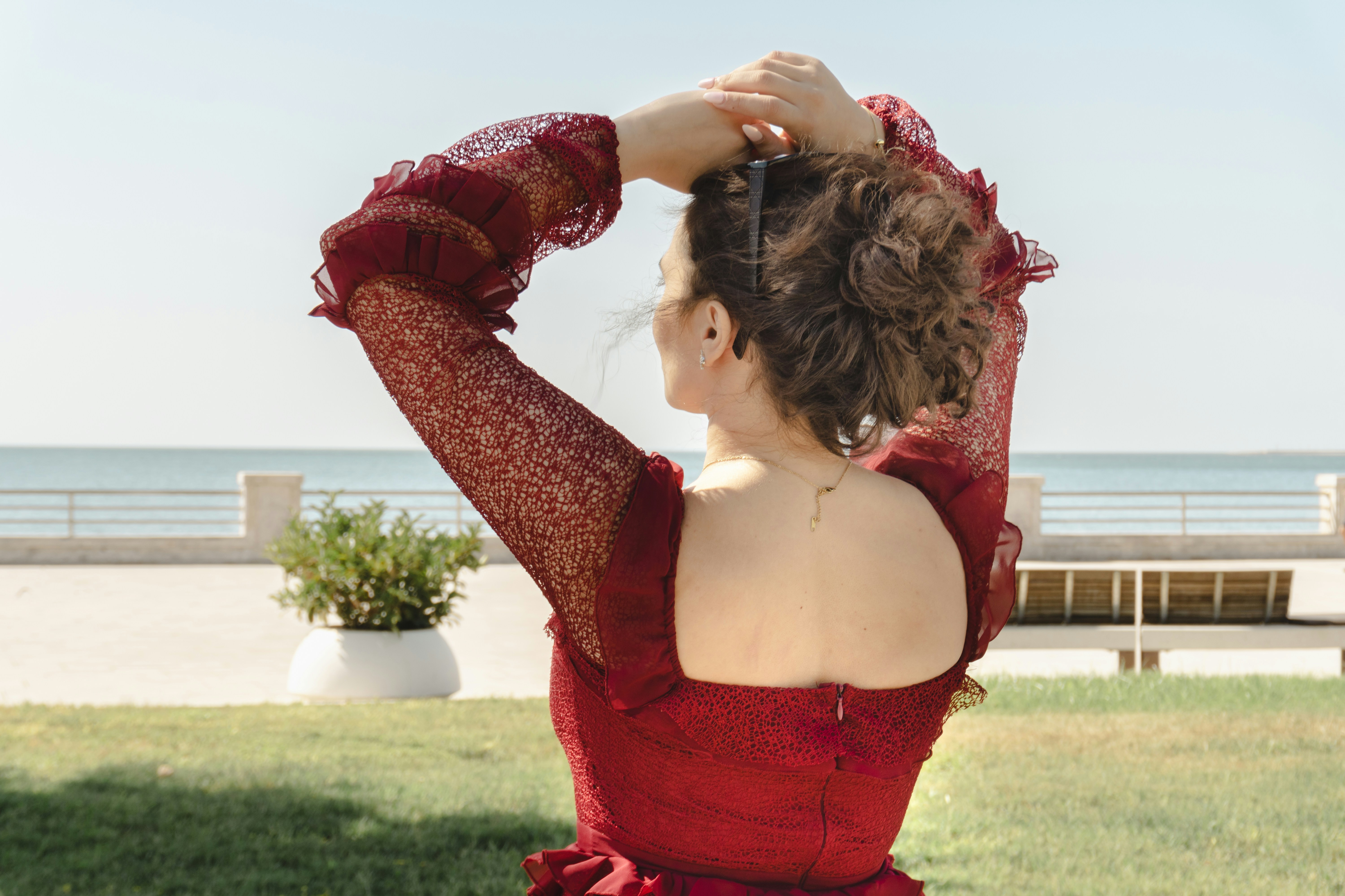Mujer con vestido rojo y manos en el mar arriba.