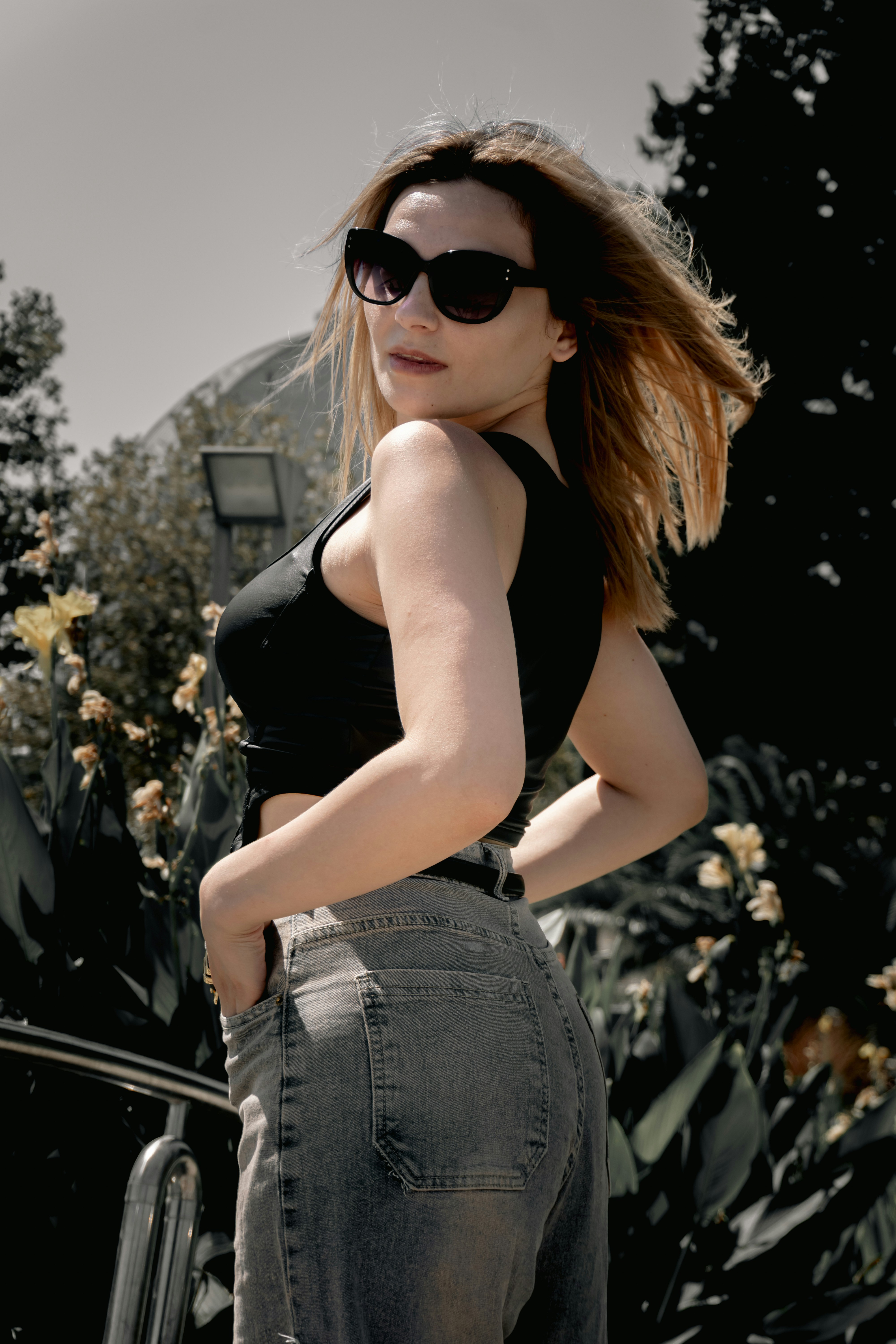 Young woman in sunglasses looking over her shoulder outdoors