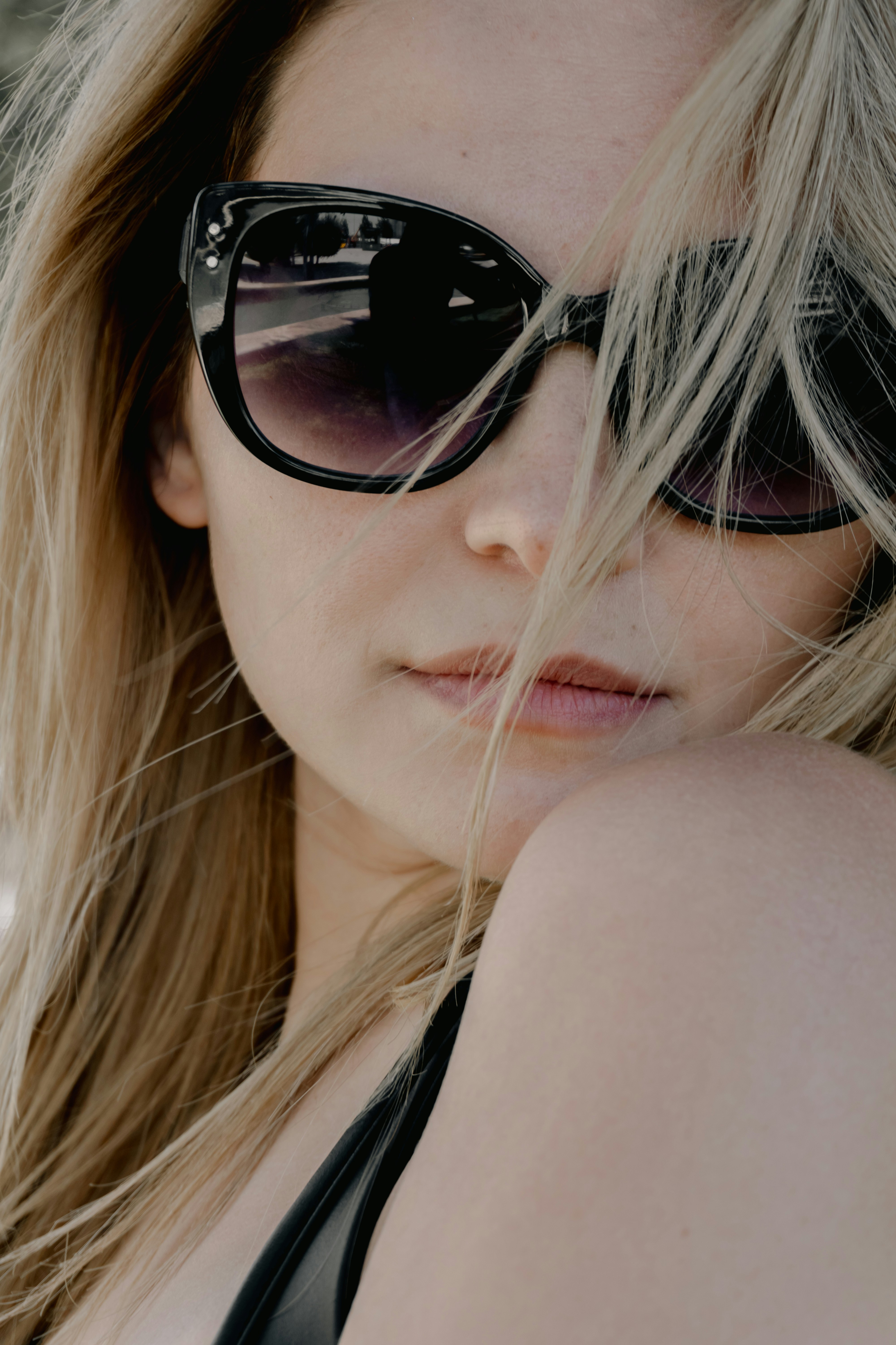 Blonde woman in sunglasses with hair across her face