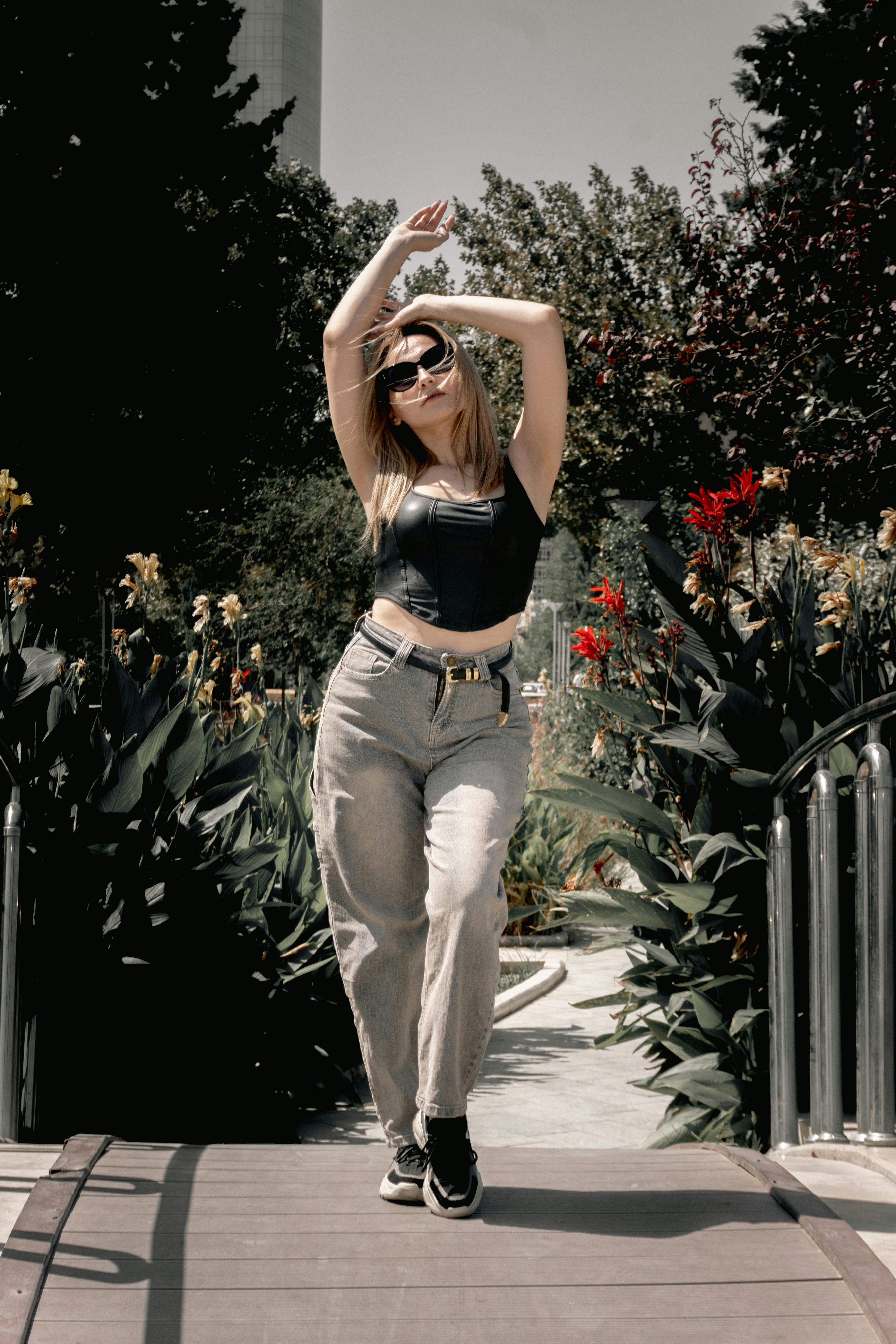 Woman in sunglasses posing on a bridge with arms raised