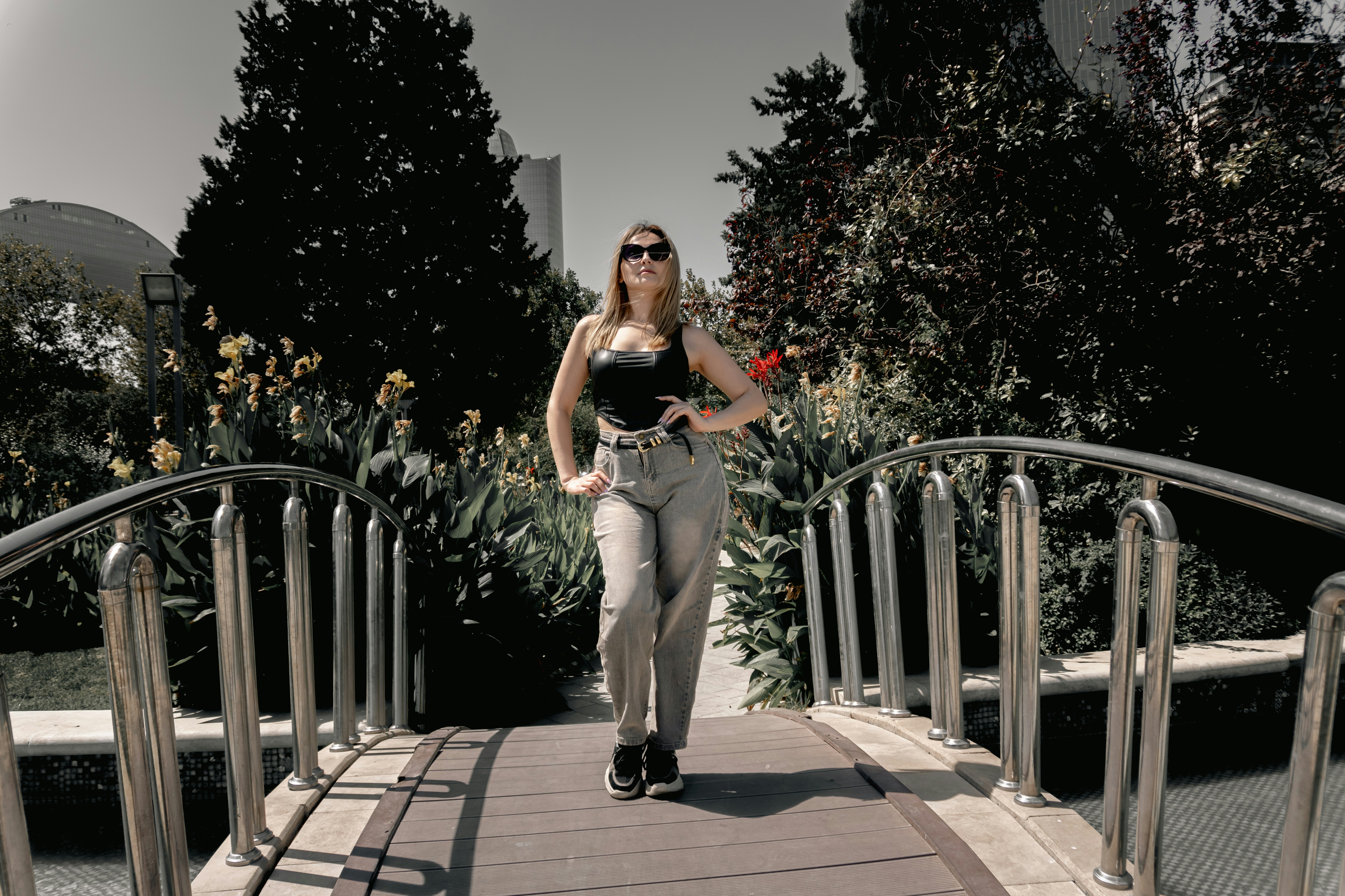 A woman walks on a bridge in a sunny park.