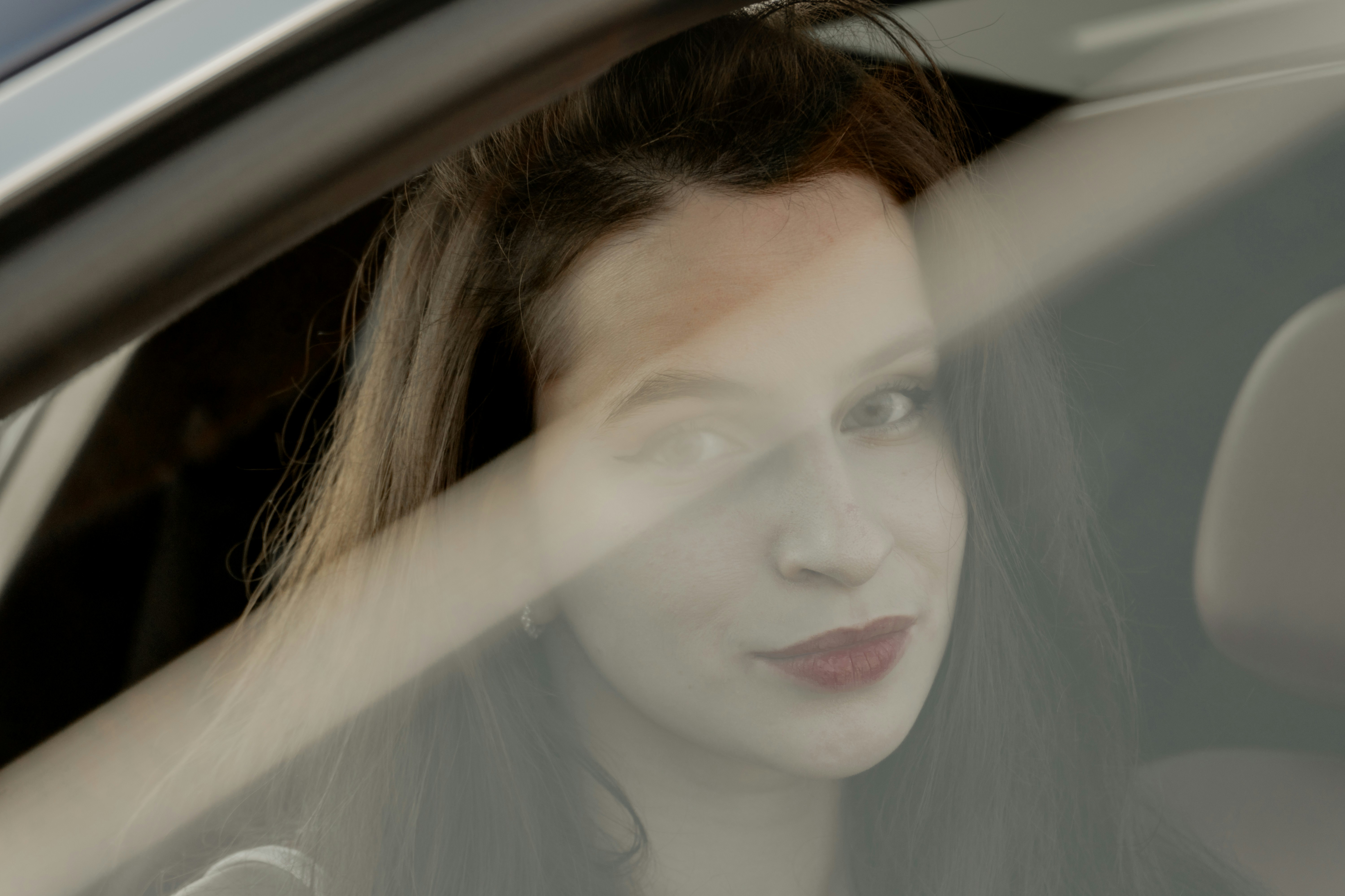 Joven con pintalabios rojo mirando por la ventana de un coche.