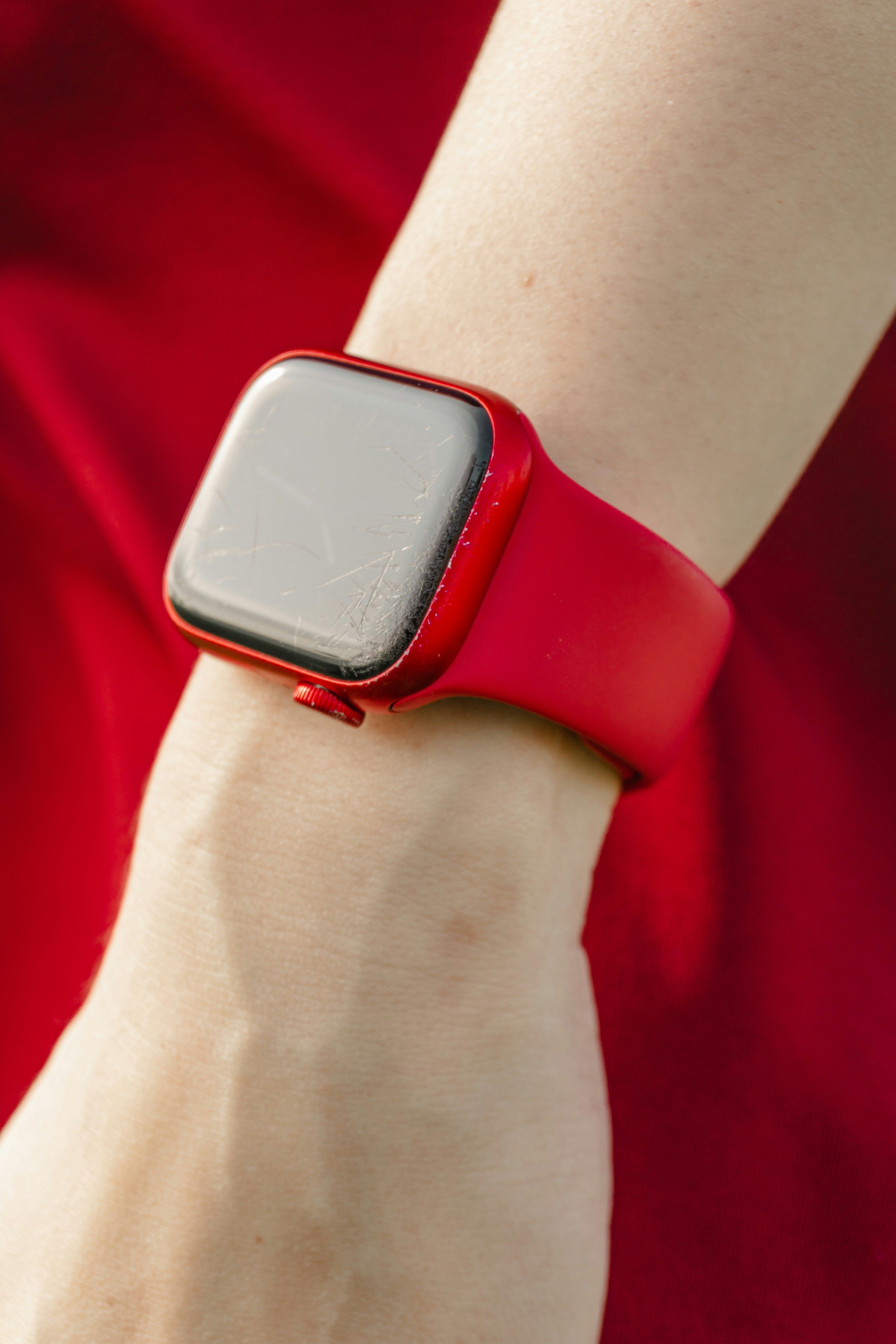 Reloj inteligente rojo agrietado en la muñeca de una persona