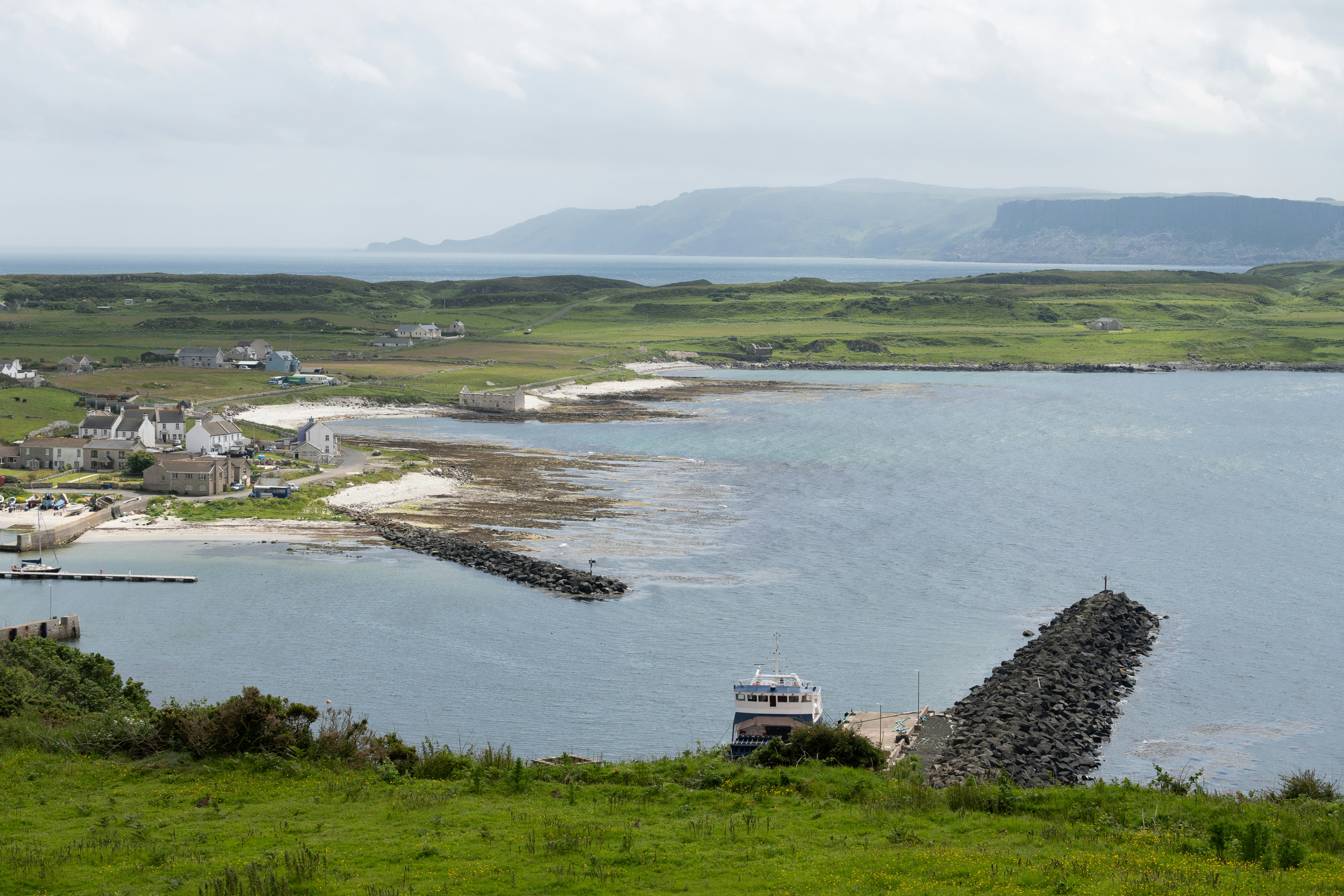 Coastal village with beaches and rocky breakwaters under cloudy sky