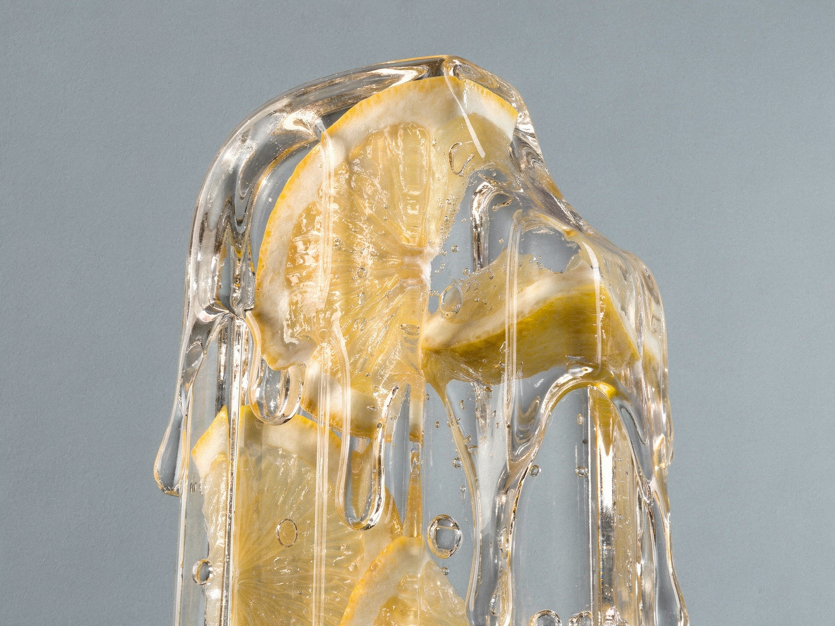 Lemon slices frozen in melting ice against a blue background.