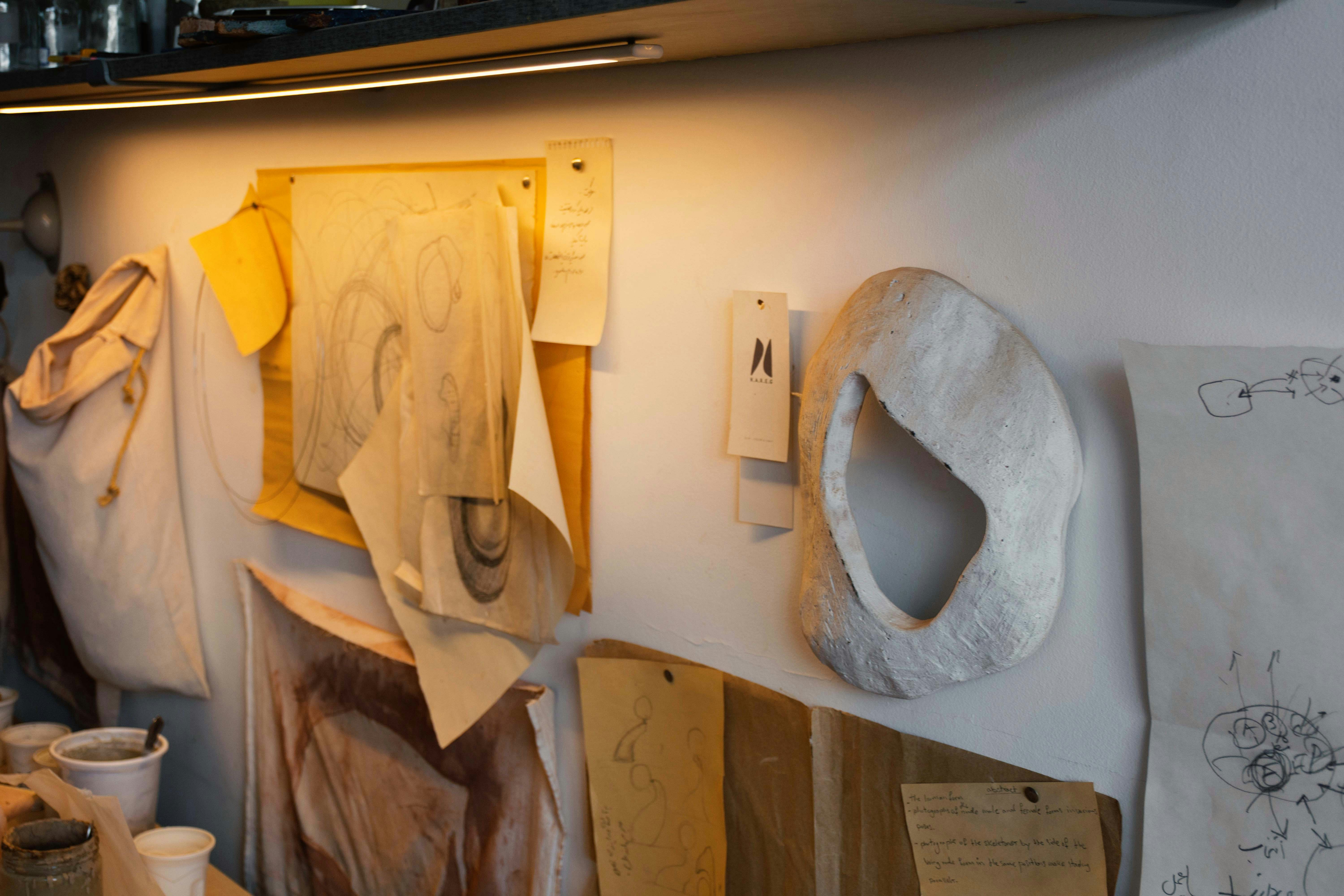 Parede do ateliê do artista com esboços e esculturas