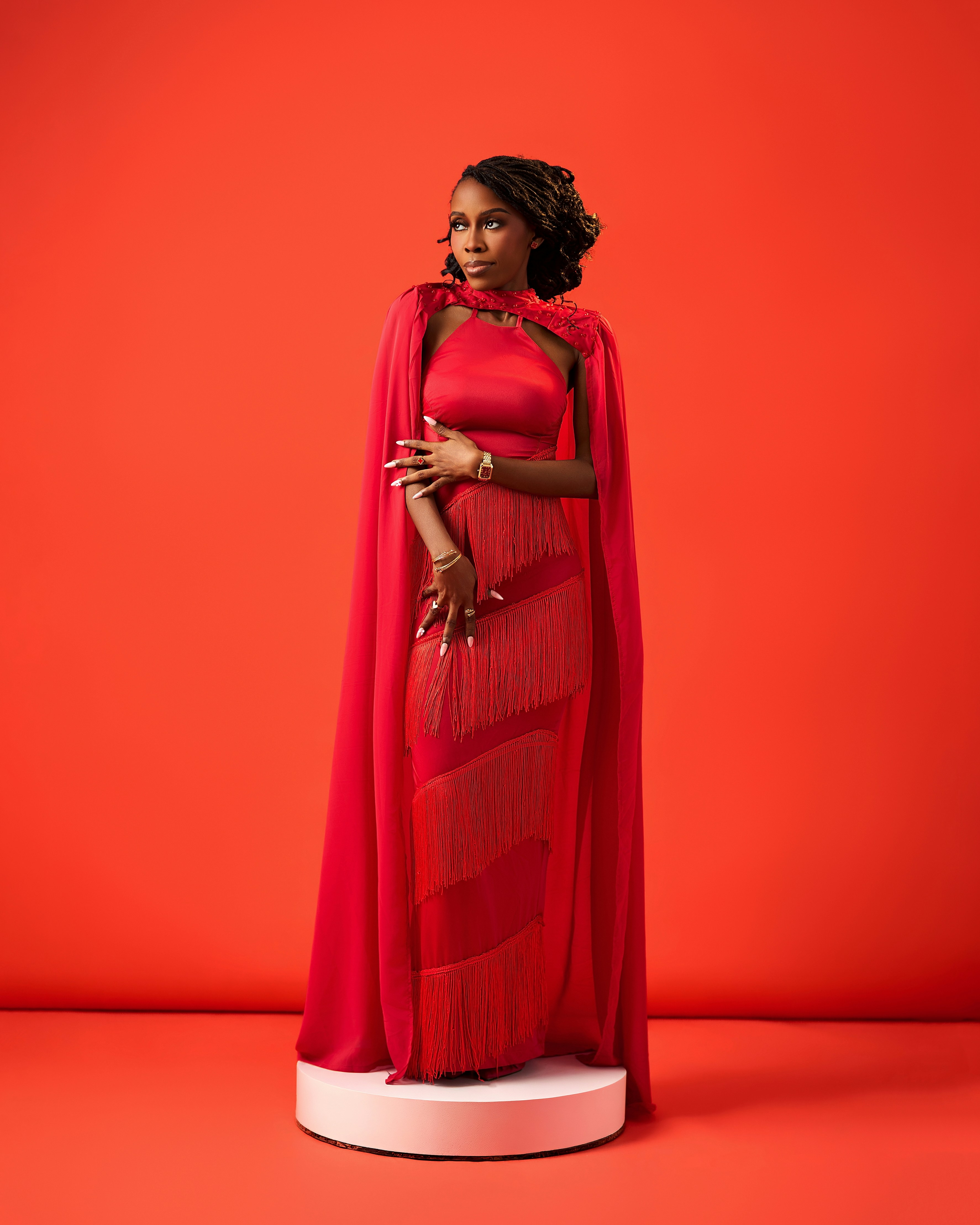 Woman in a stunning red dress and cape on pedestal