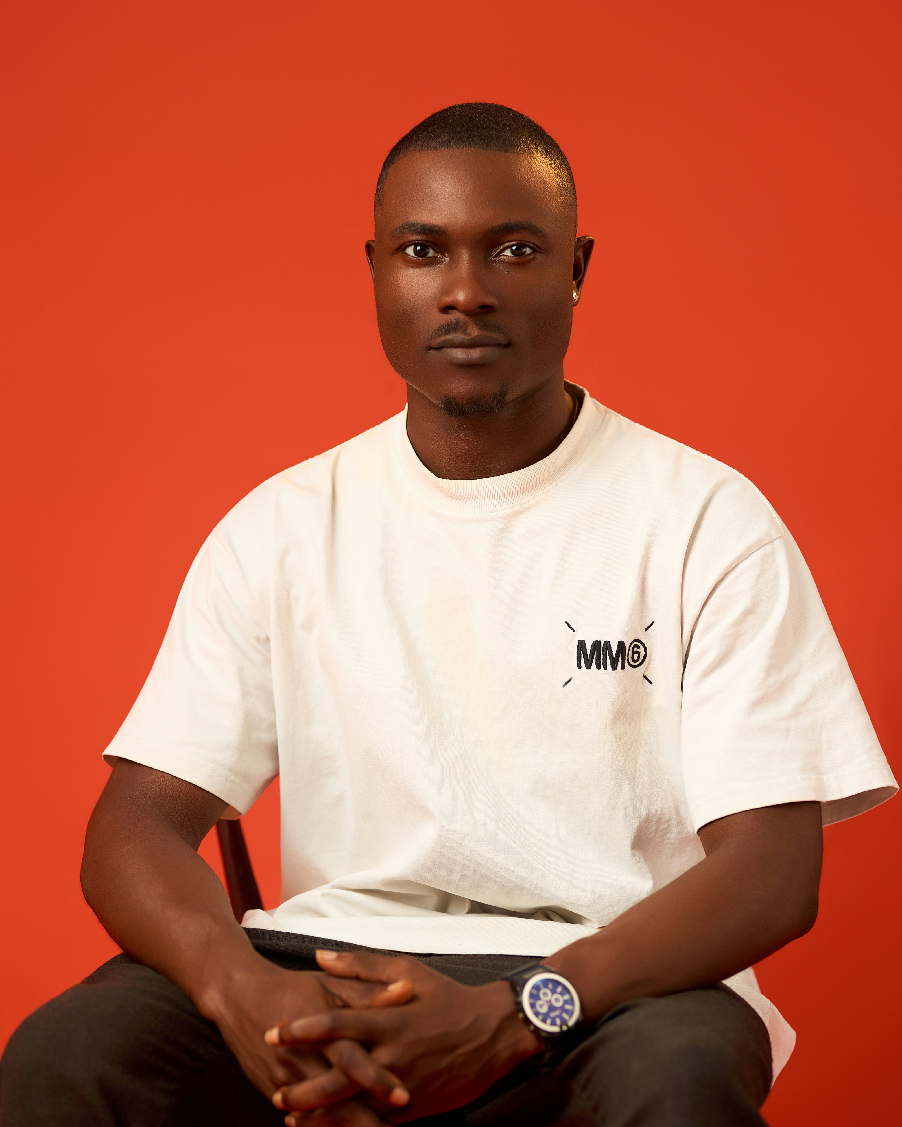 A man on white shirt and a red backdrop