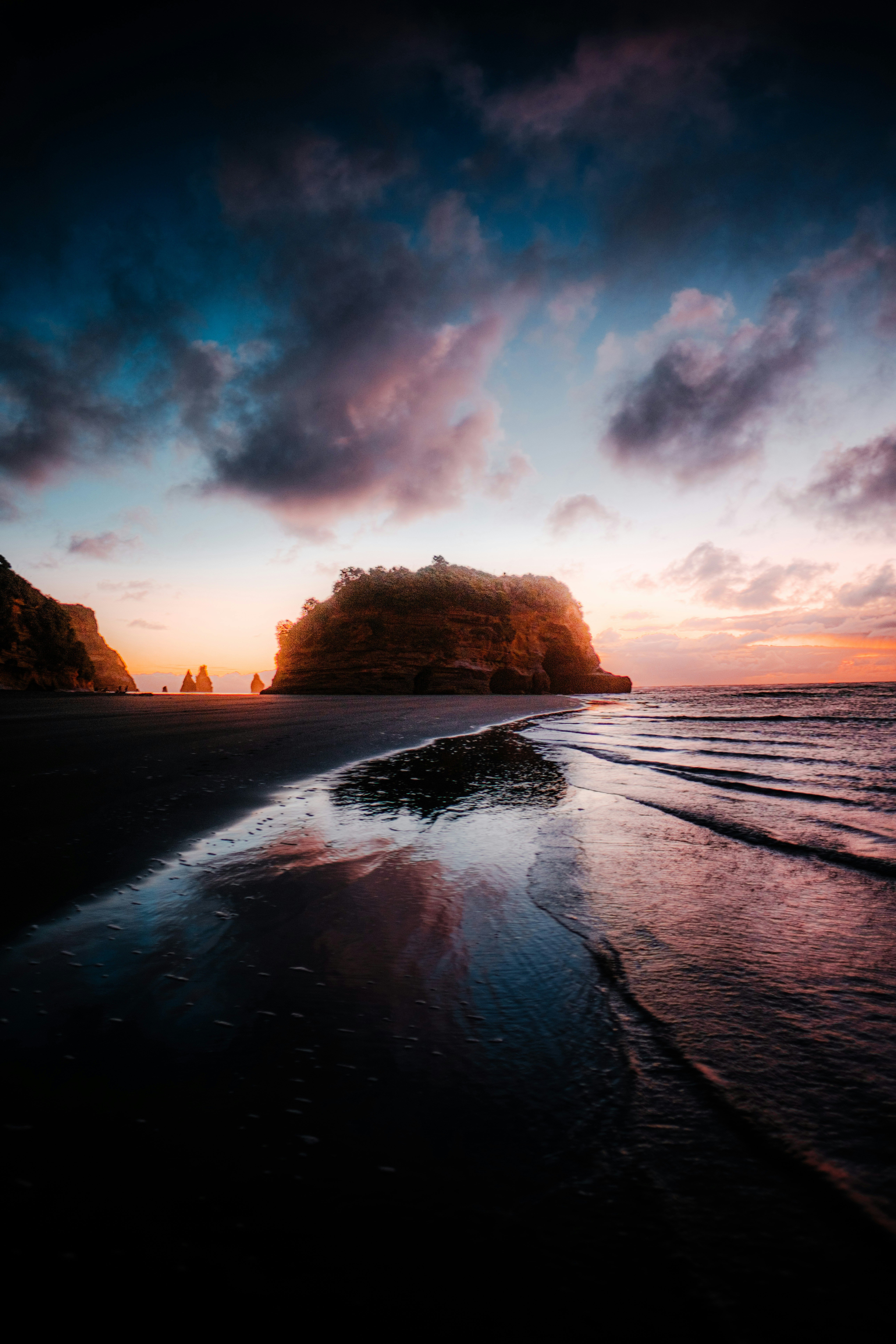 Photo of Dramatic sunset over a beach with a large rock formation. by Jan Folwarczny