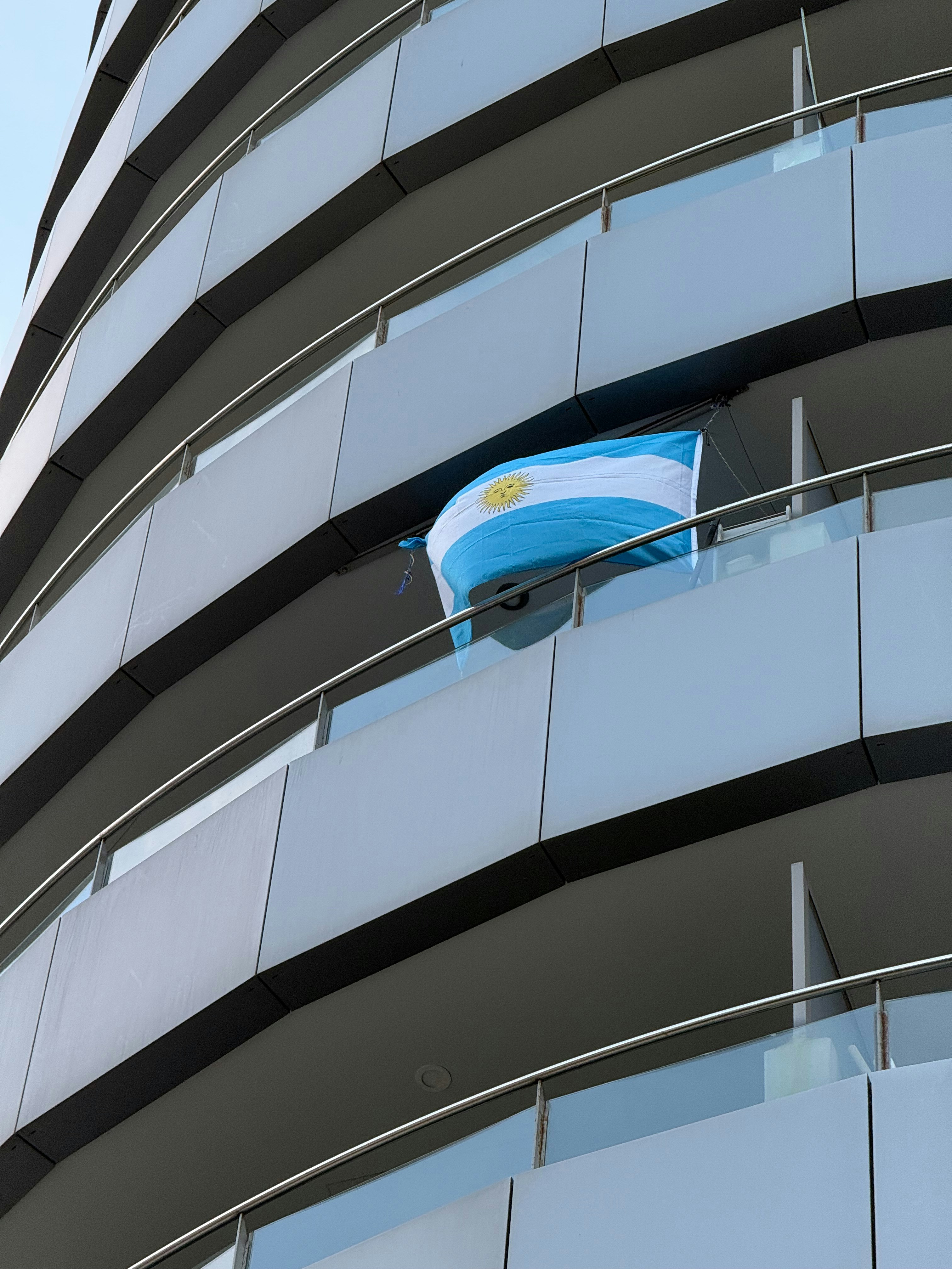 Drapeau argentin suspendu au balcon d’un bâtiment moderne.