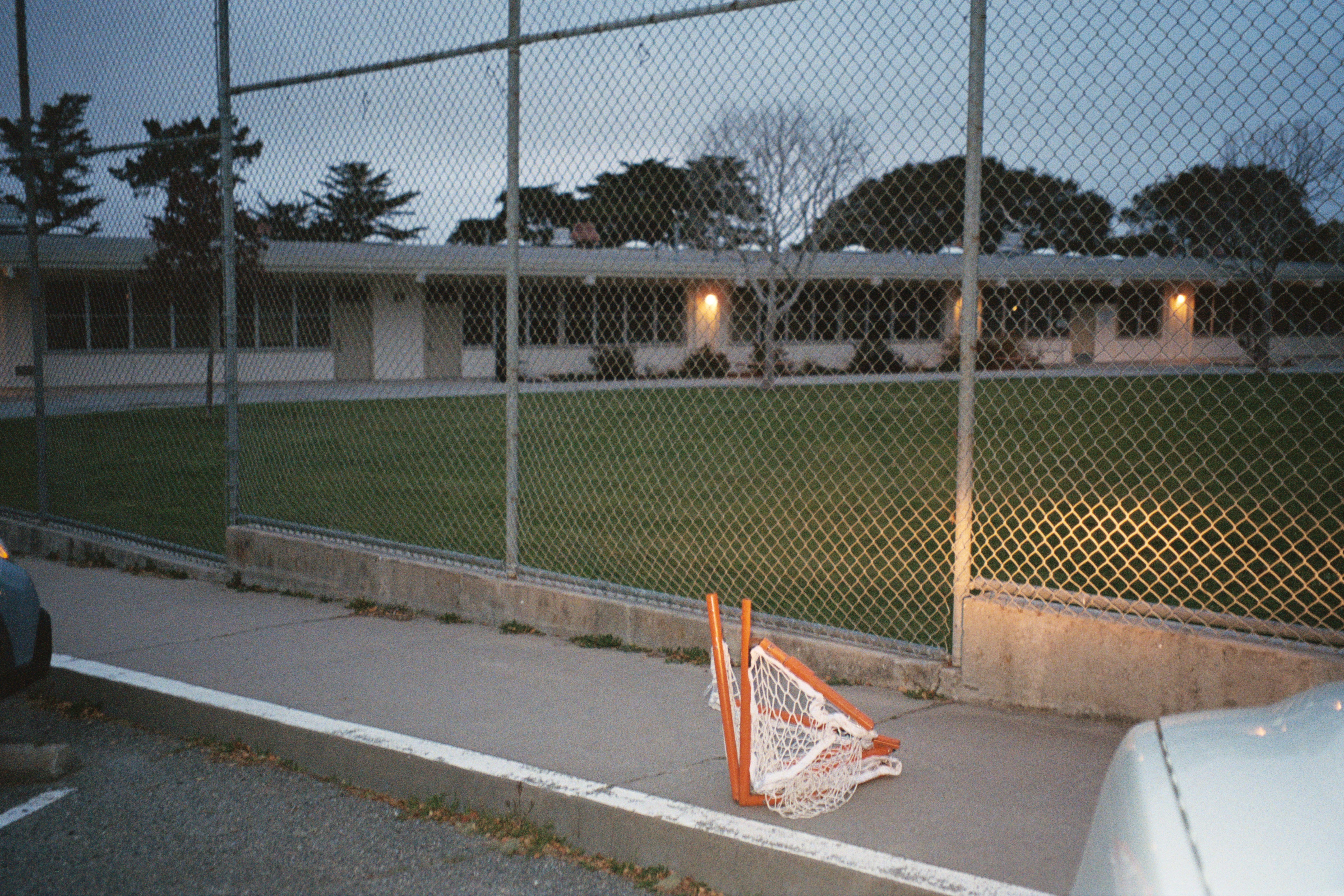 Gawang lacrosse di trotoar di sebelah gedung sekolah dan lapangan.