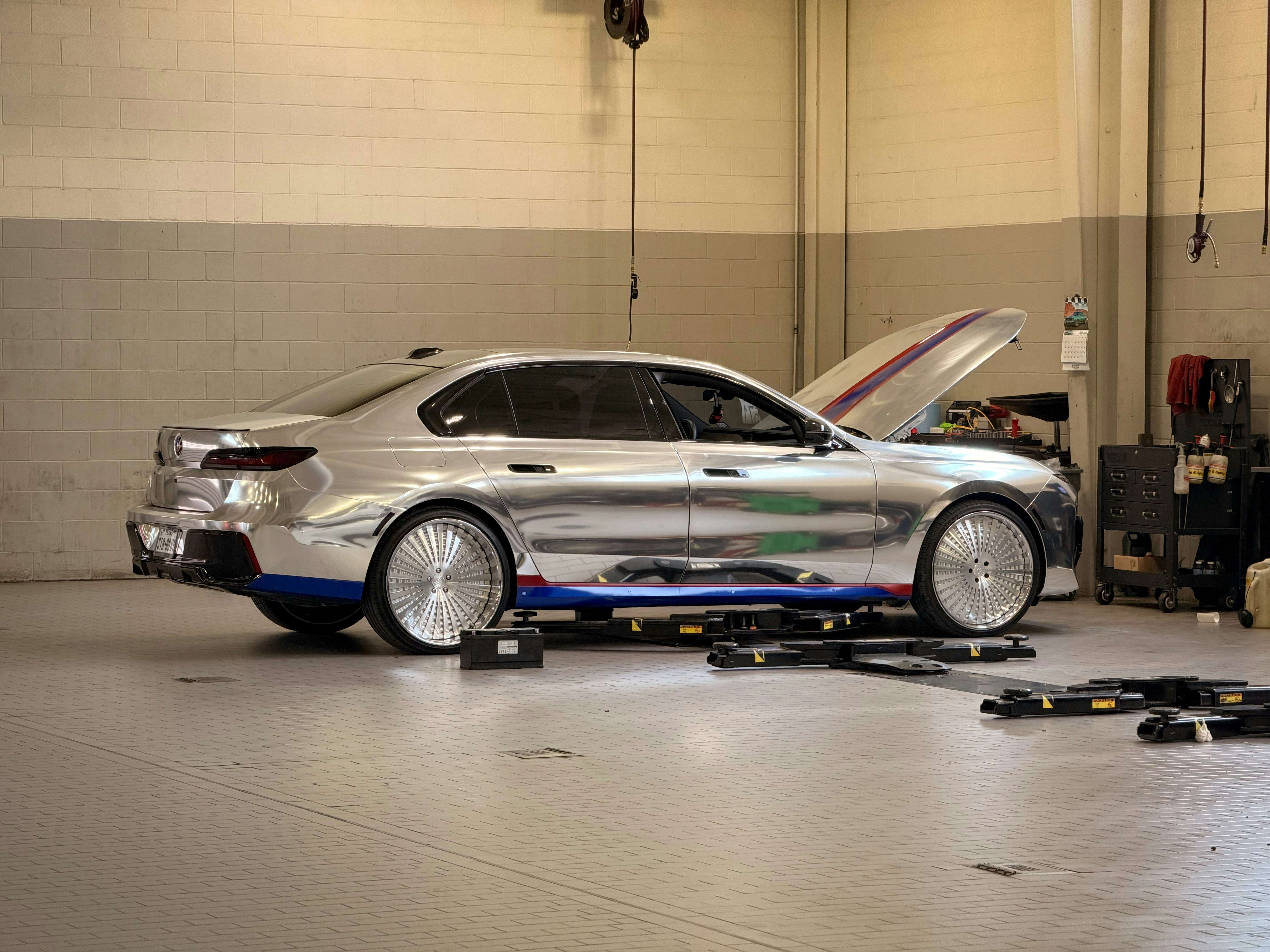 Ein verchromtes Auto mit offener Motorhaube in einer Garage.