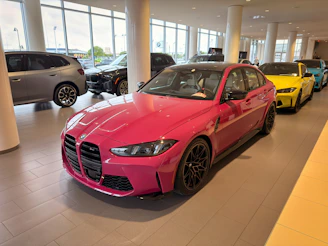 A vibrant pink car displayed prominently in a modern showroom.