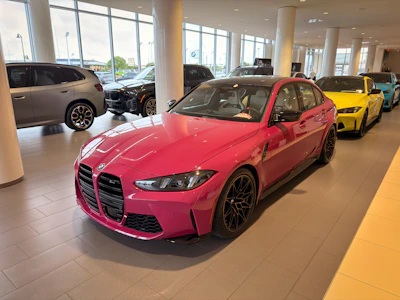 A vibrant pink car displayed prominently in a modern showroom.