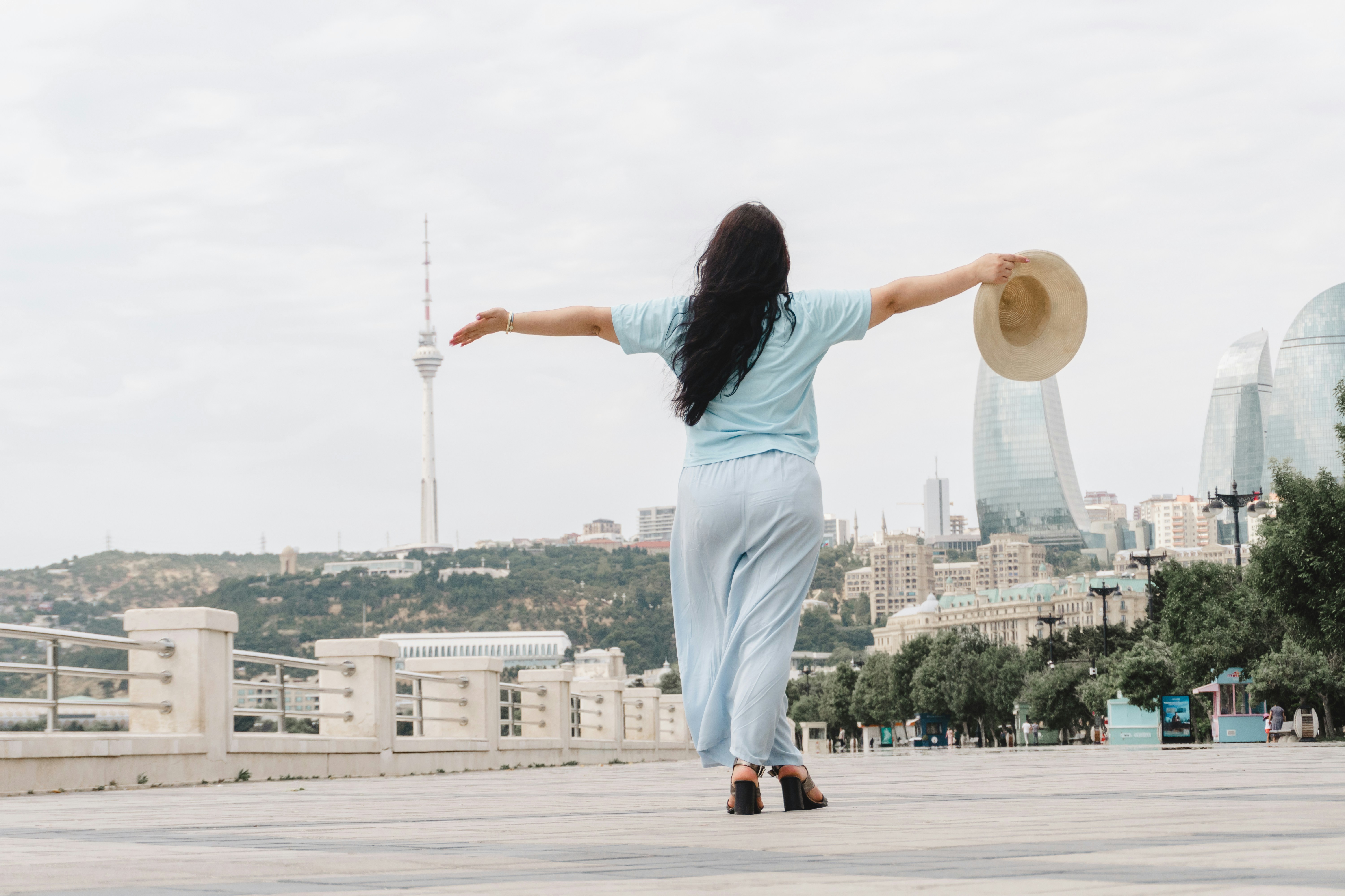 Woman with arms outstretched, walking towards a city skyline.