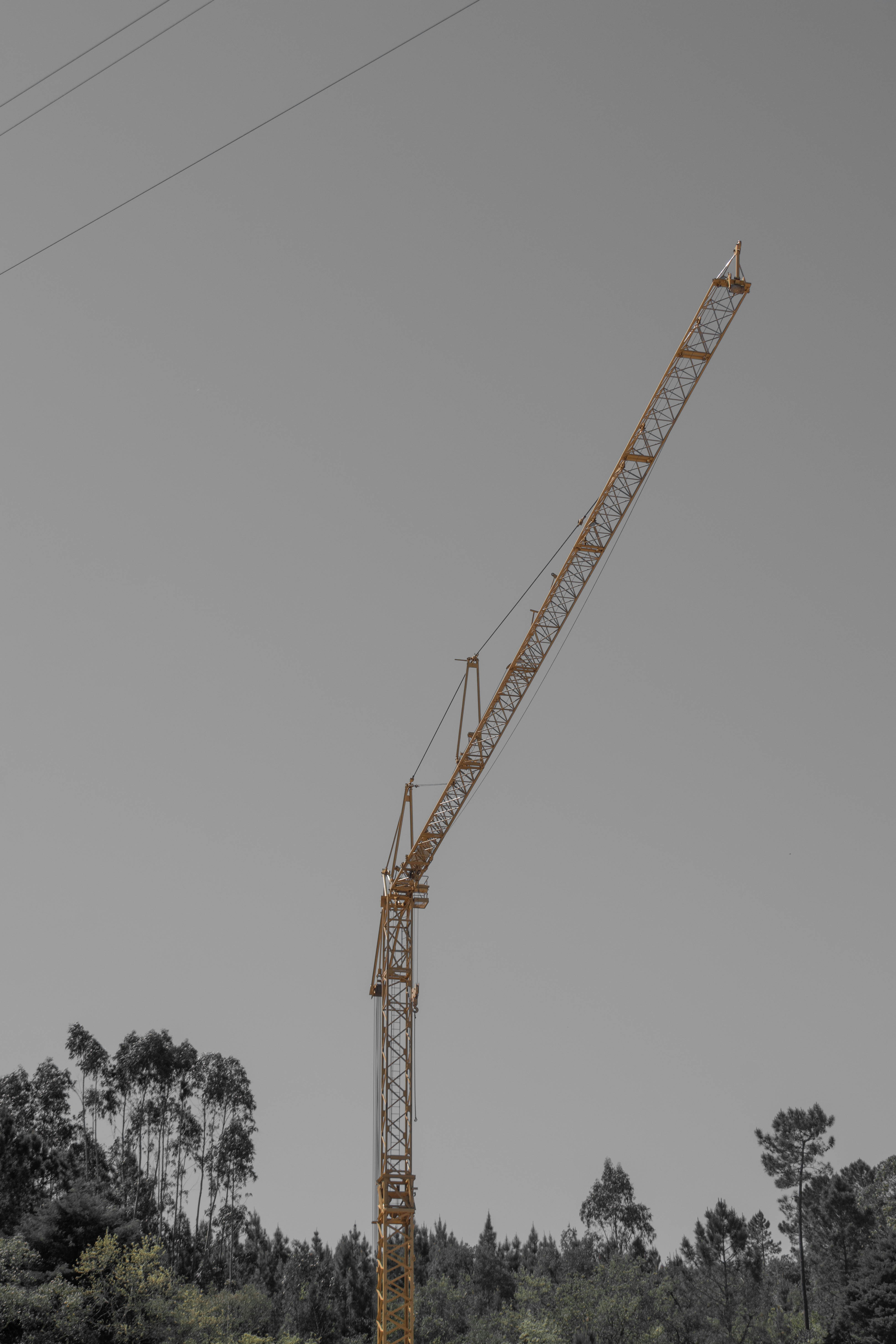 Bright yellow construction crane against a grey sky