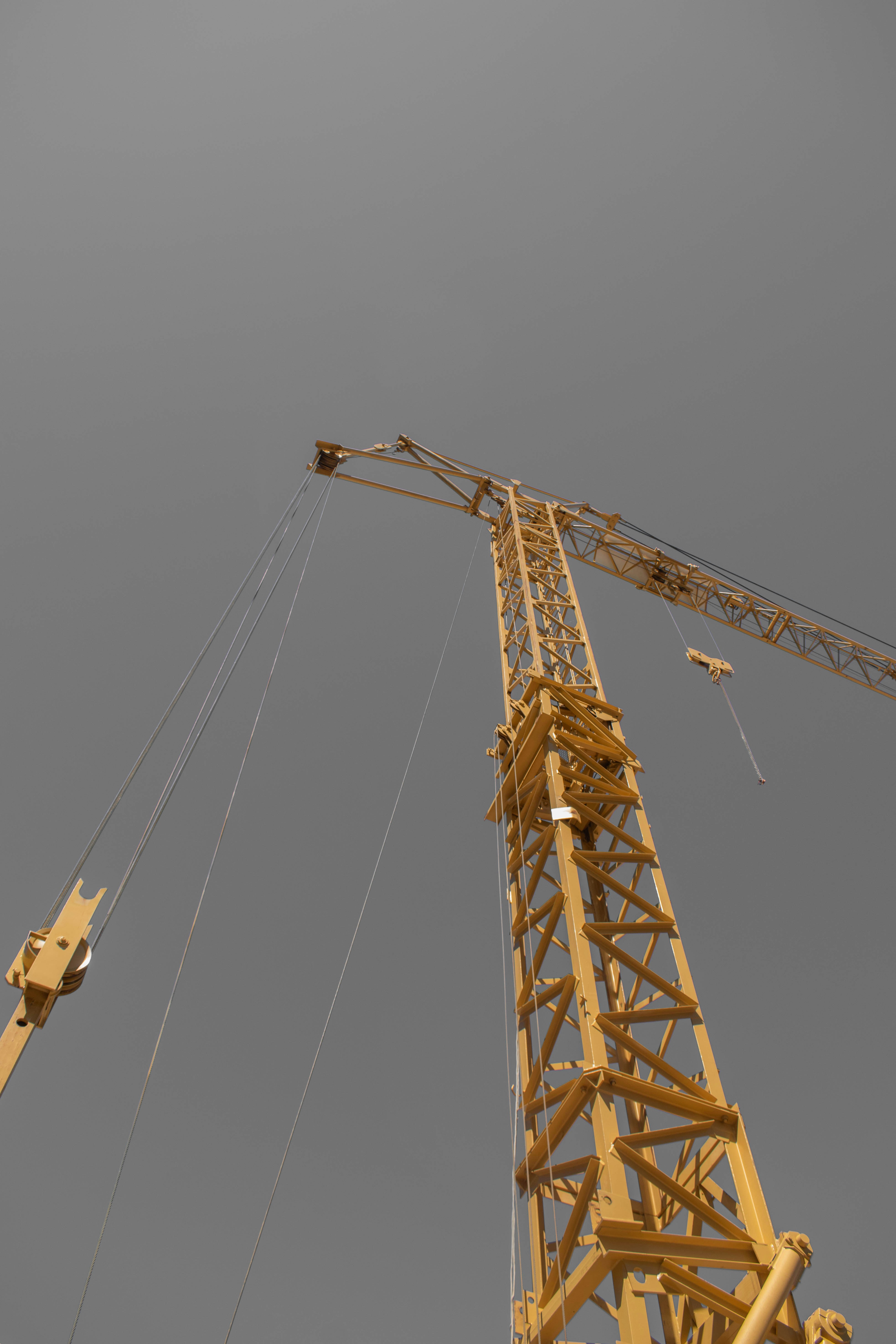 A tall yellow construction crane against a grey sky
