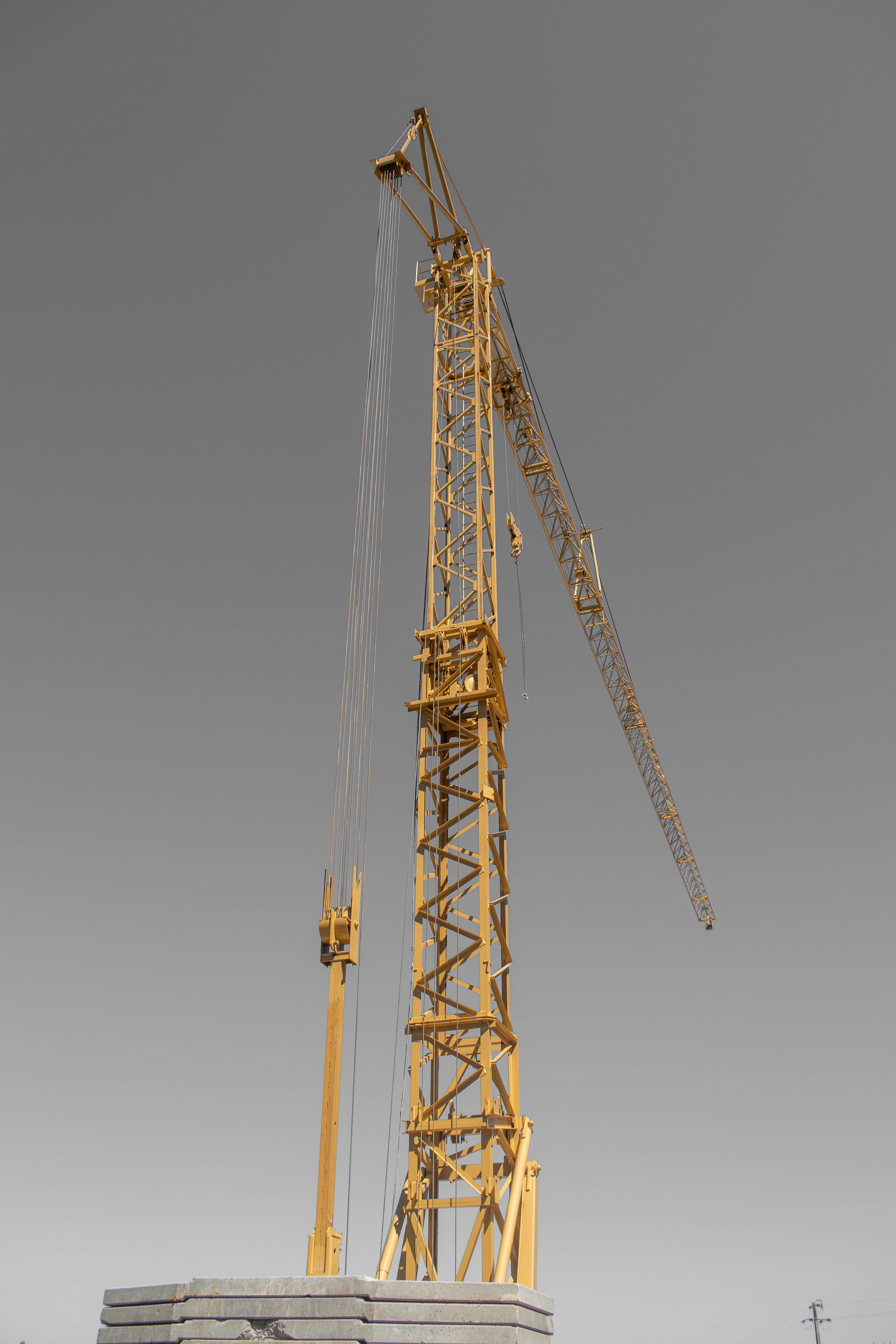 A tall yellow construction crane stands against a grey sky