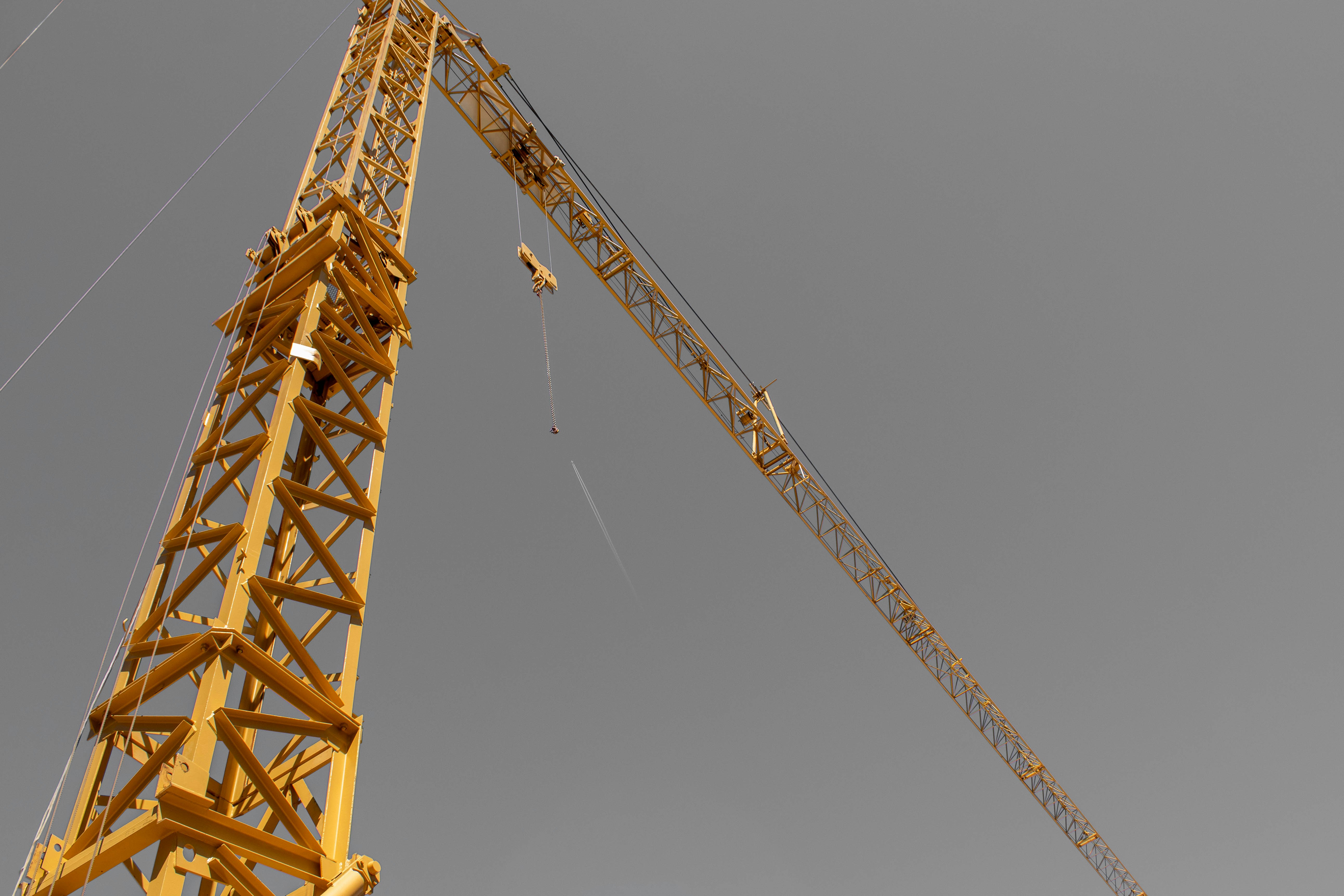 A tall yellow construction crane against a grey sky