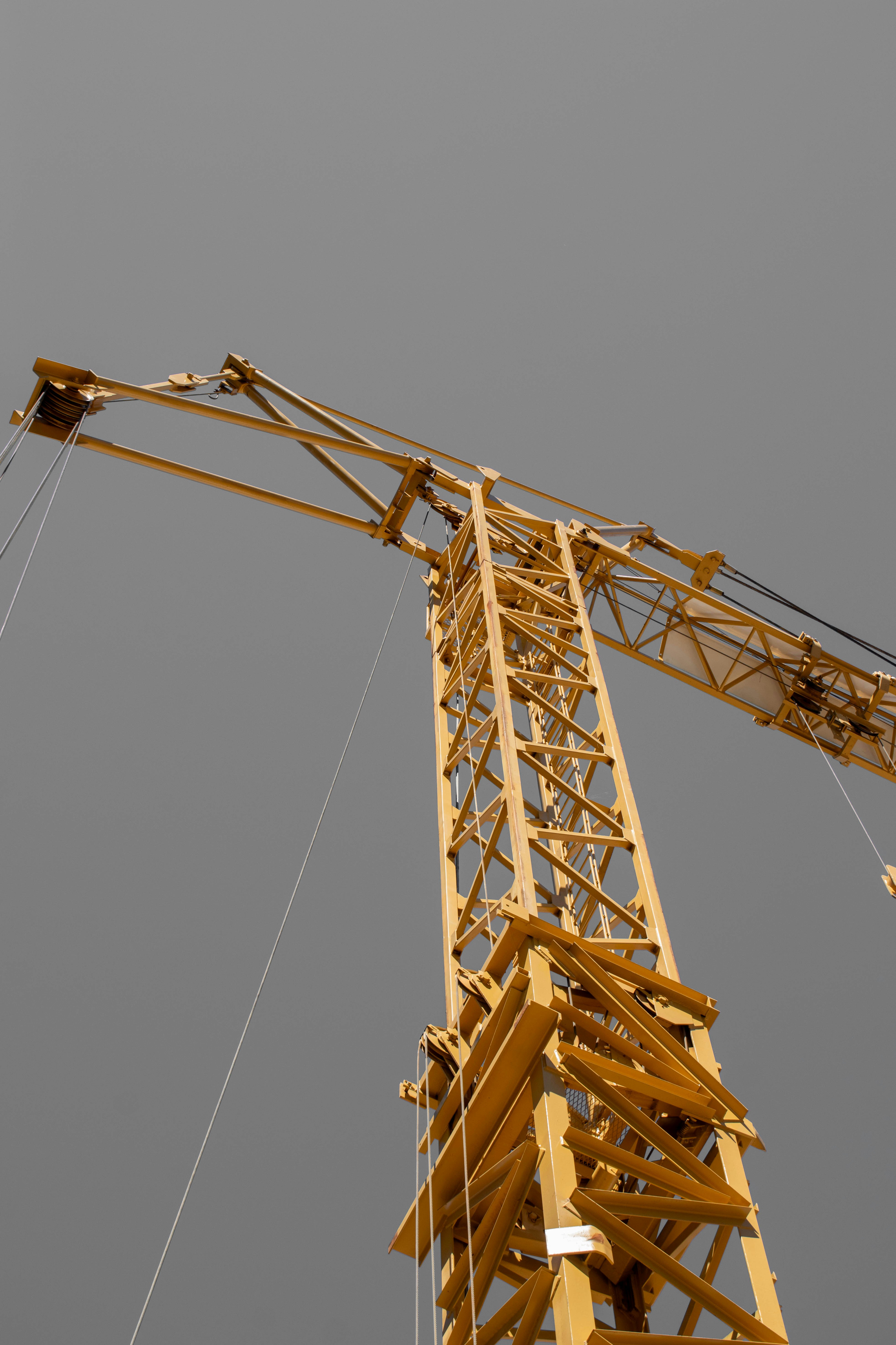 A yellow construction crane stands tall against a grey sky