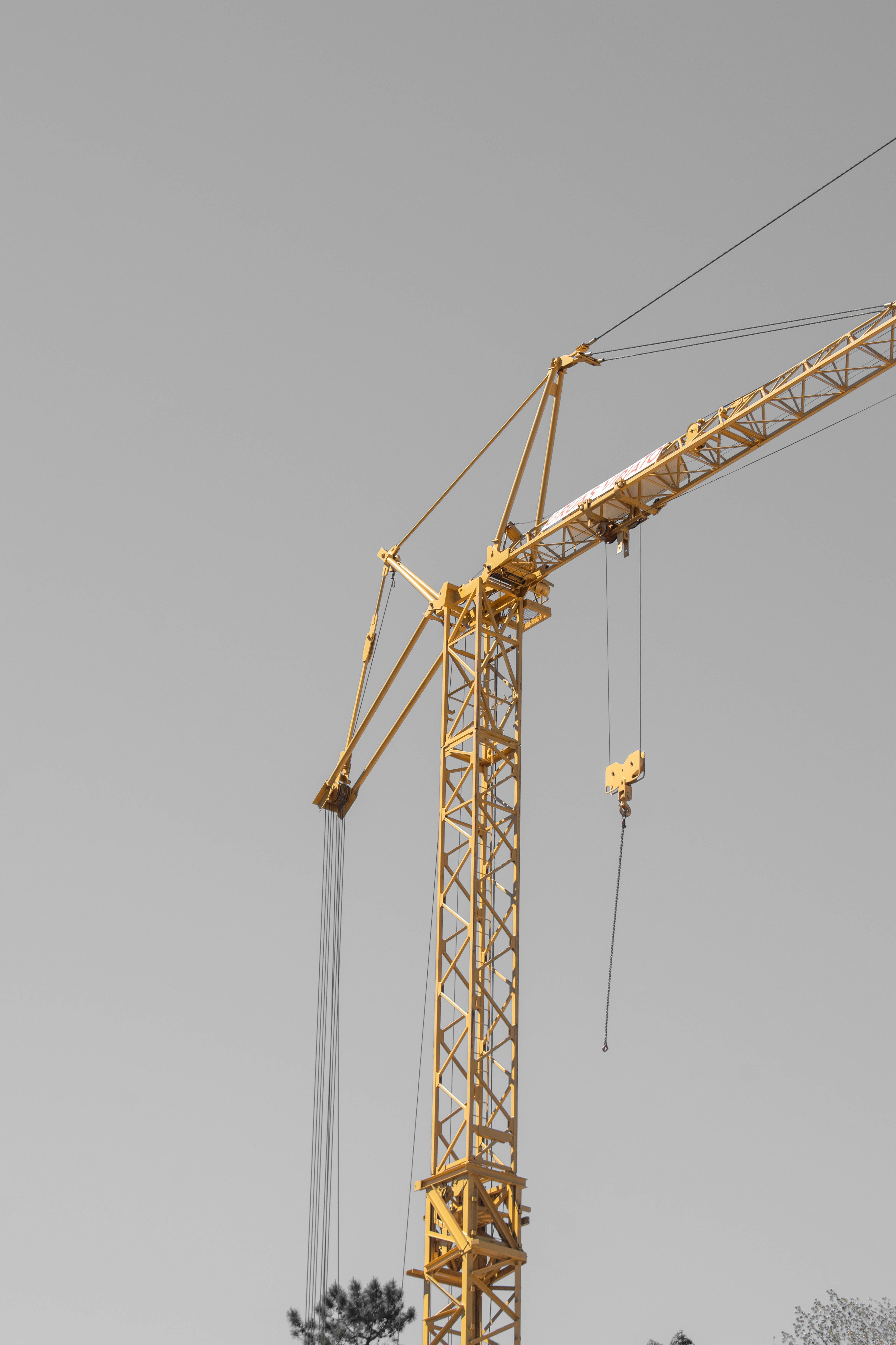 A yellow construction crane stands tall against a grey sky