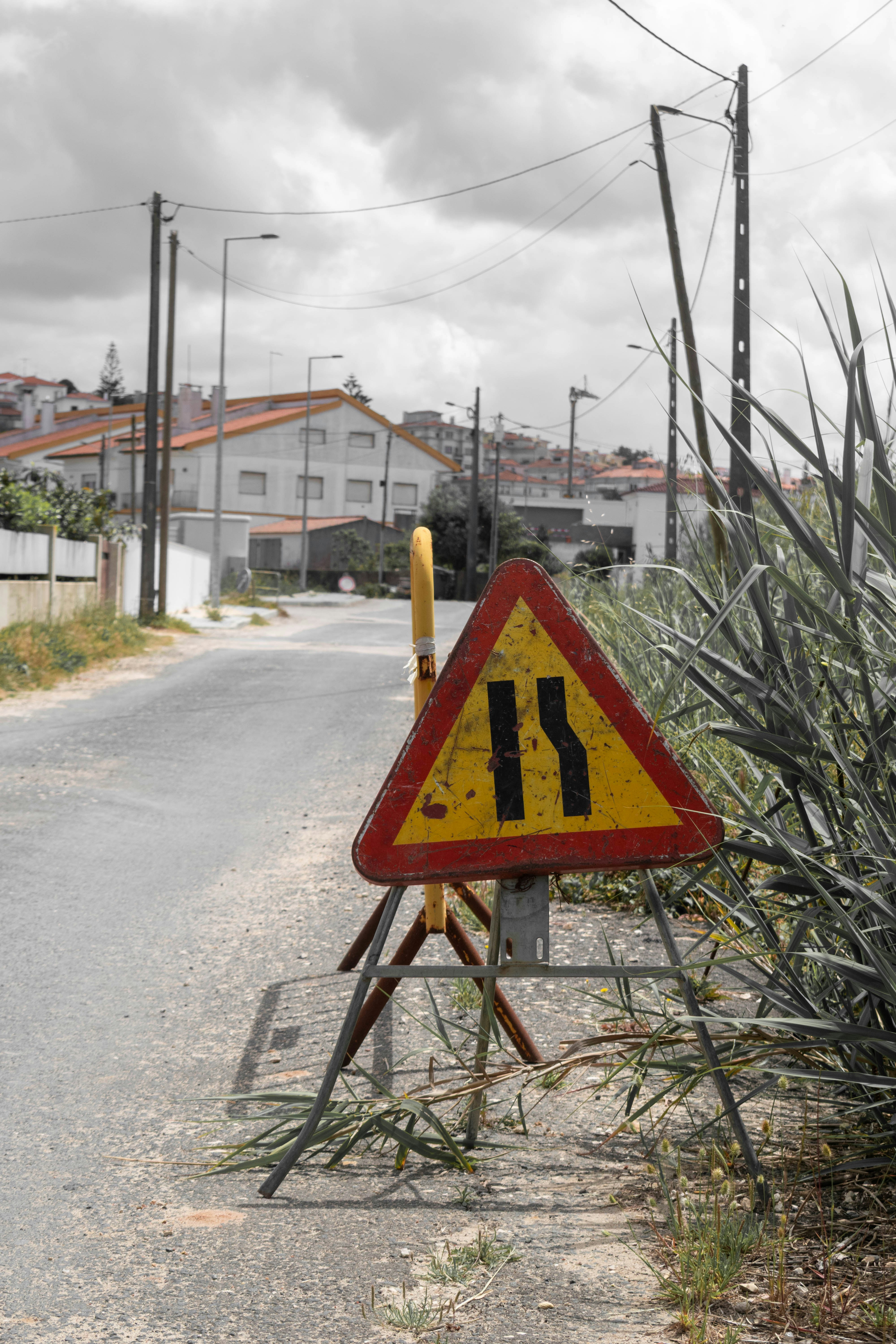 A yellow road narrows sign on a rural road