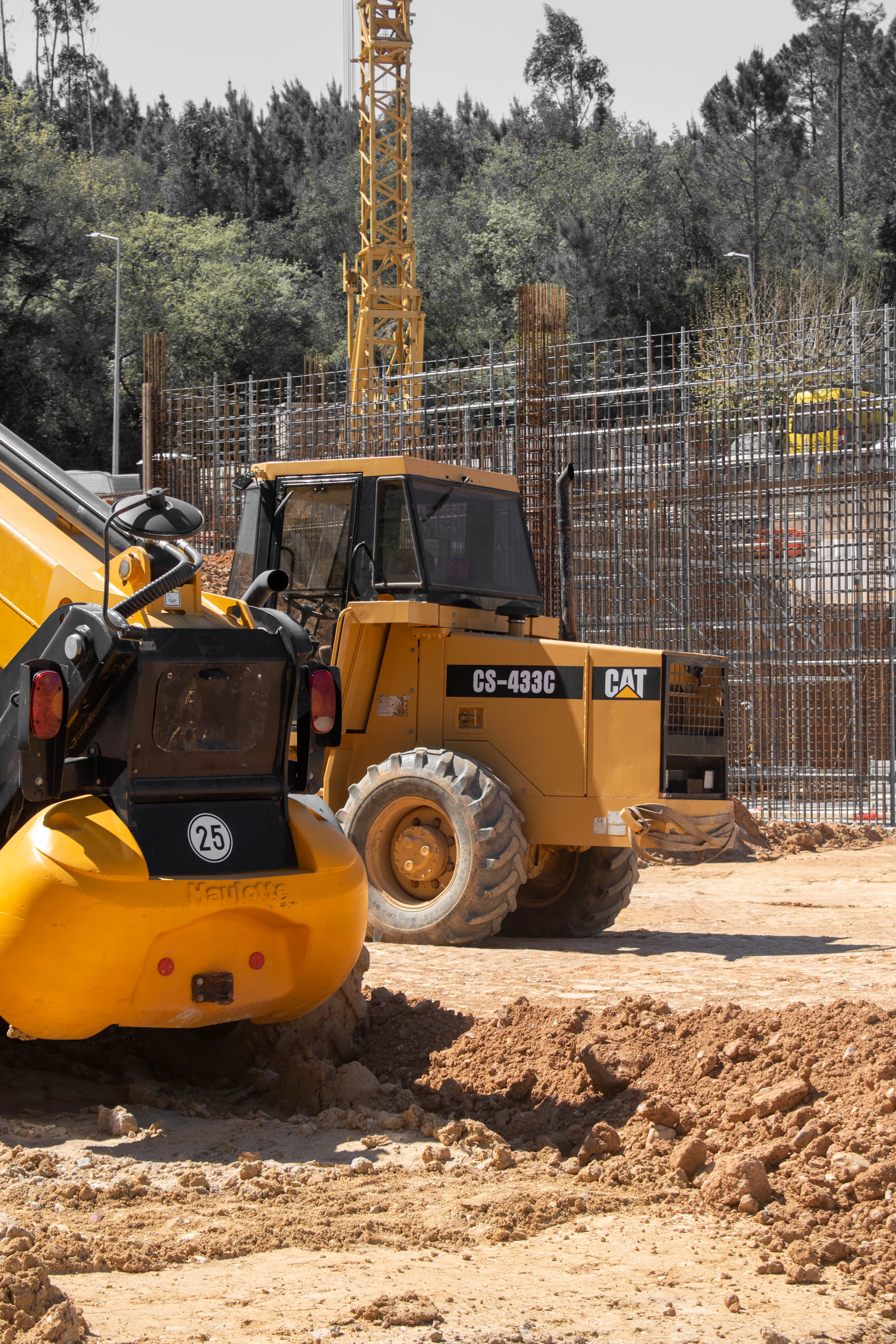Yellow construction vehicles and crane at a dusty building site