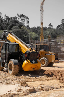 Two yellow construction vehicles on a muddy construction site