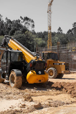 Two yellow construction vehicles on a muddy construction site