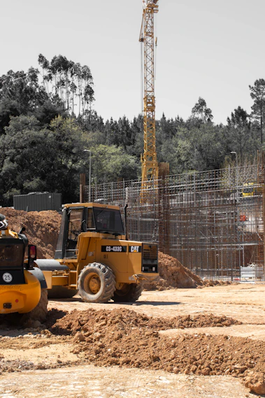 Yellow construction vehicle and crane at a building site.