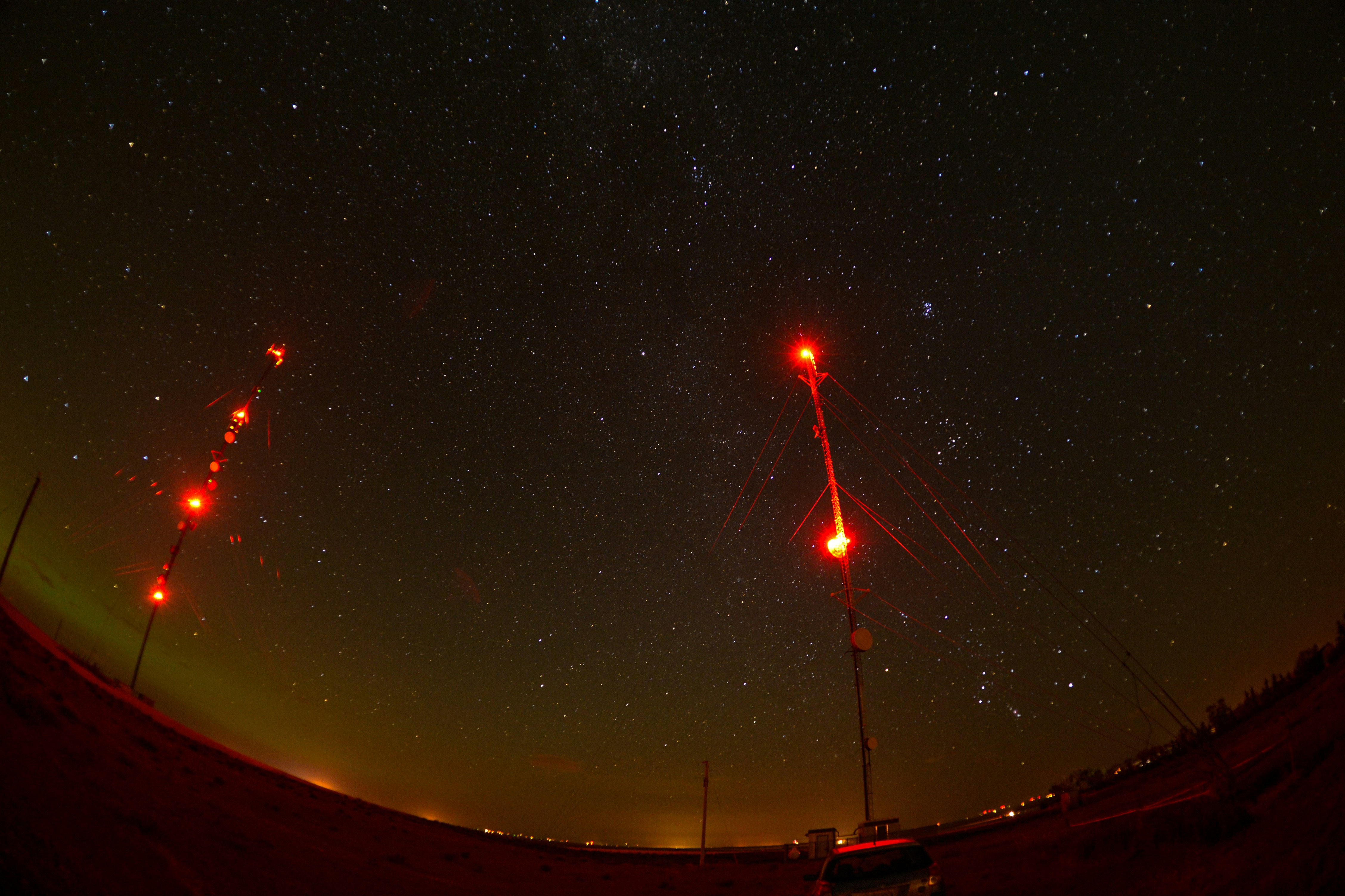 Cielo stellato con luci rosse di avvertimento sulle torri di comunicazione.