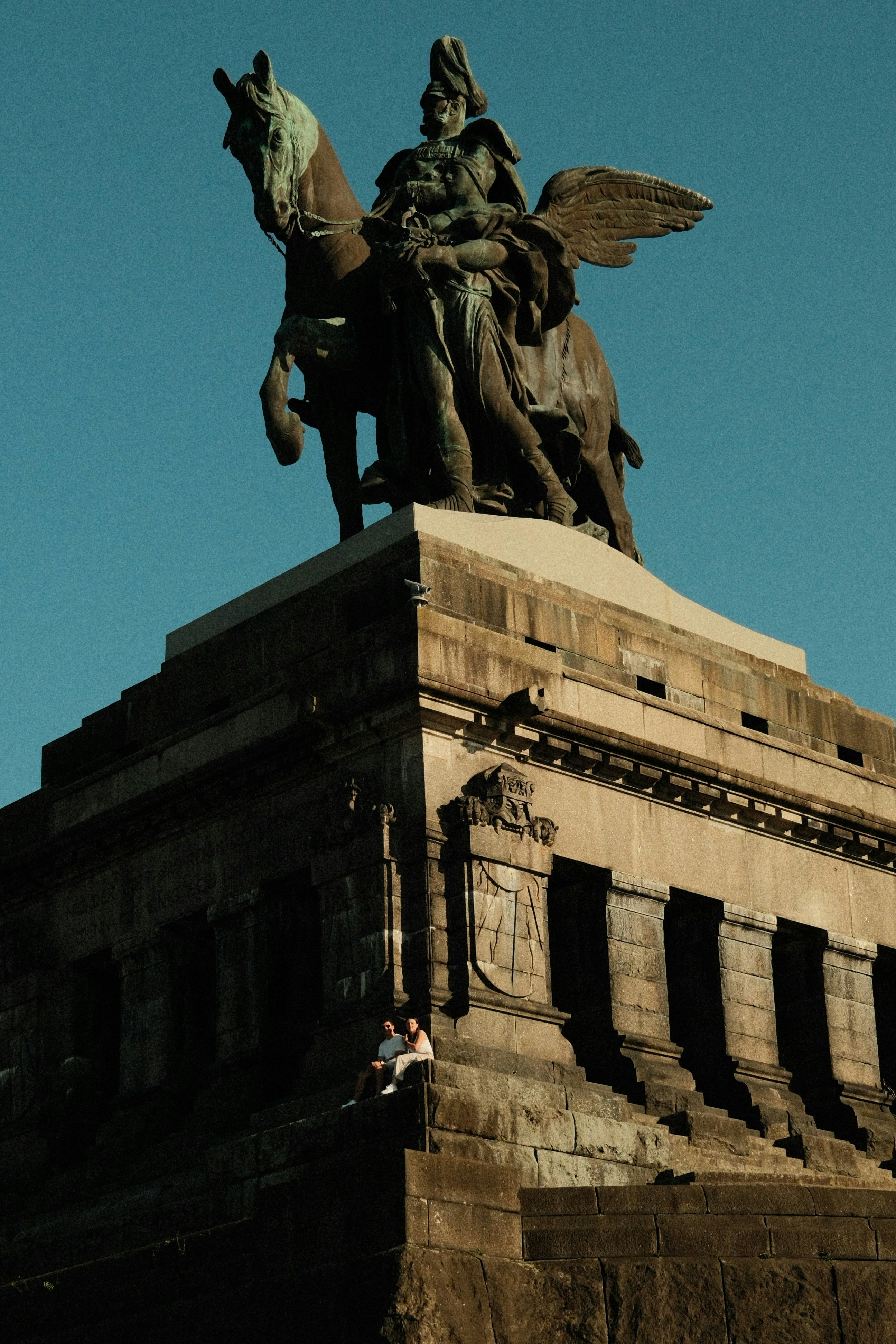Monumental equestrian statue with people sitting on its stone base
