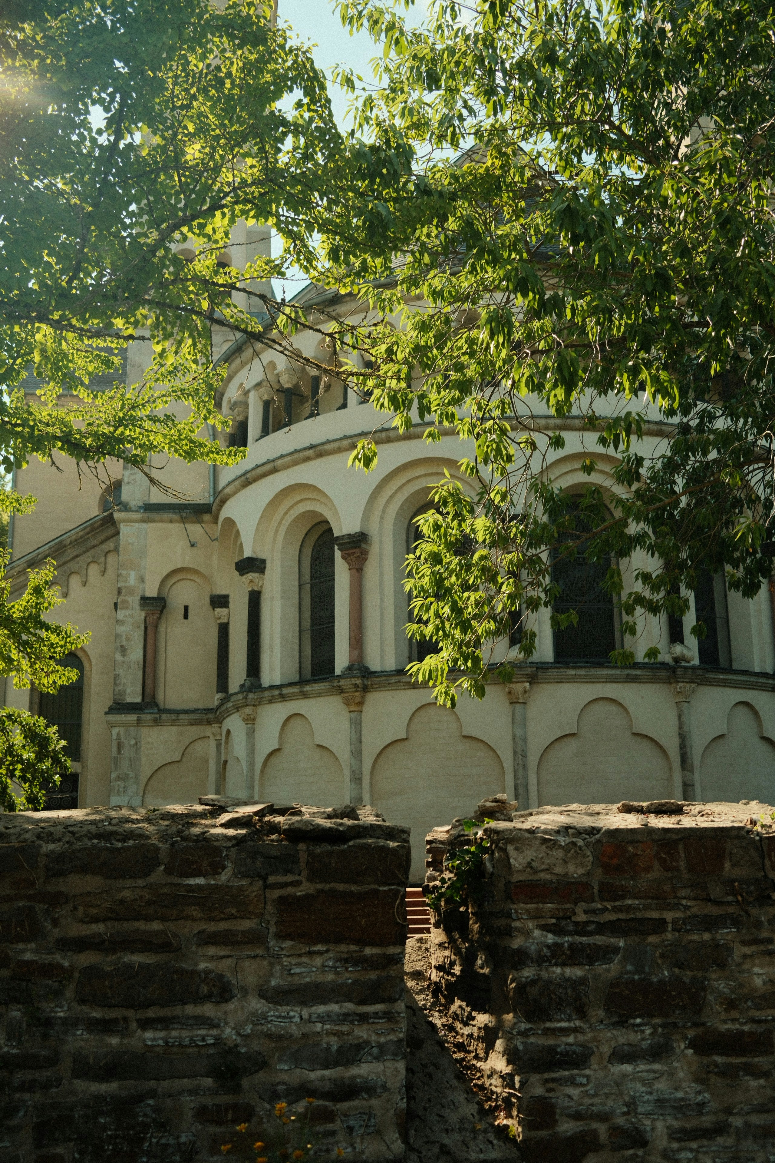 Ancient stone church behind a weathered wall and green foliage
