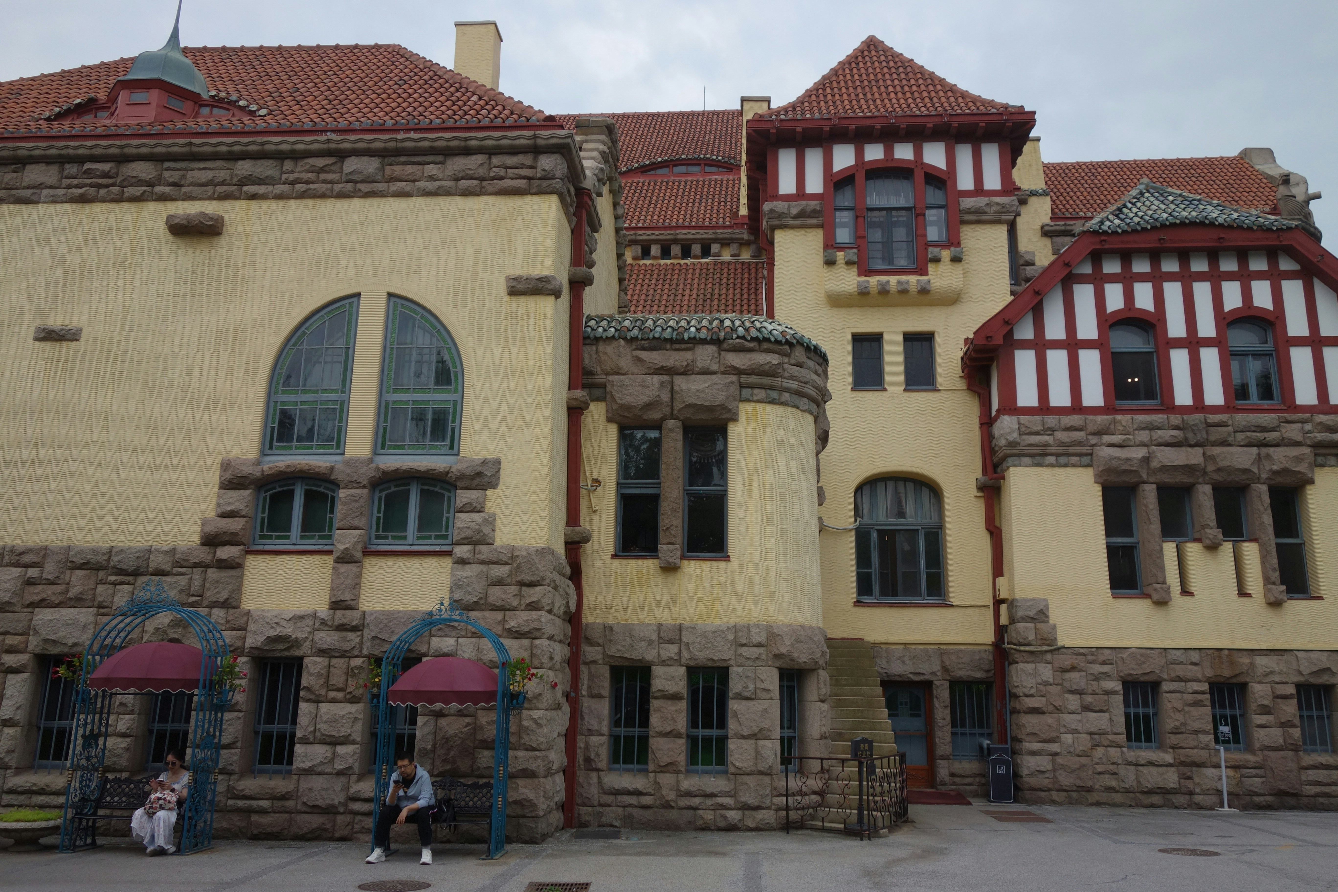 Historic building with yellow facade, stone foundation, and red roof.