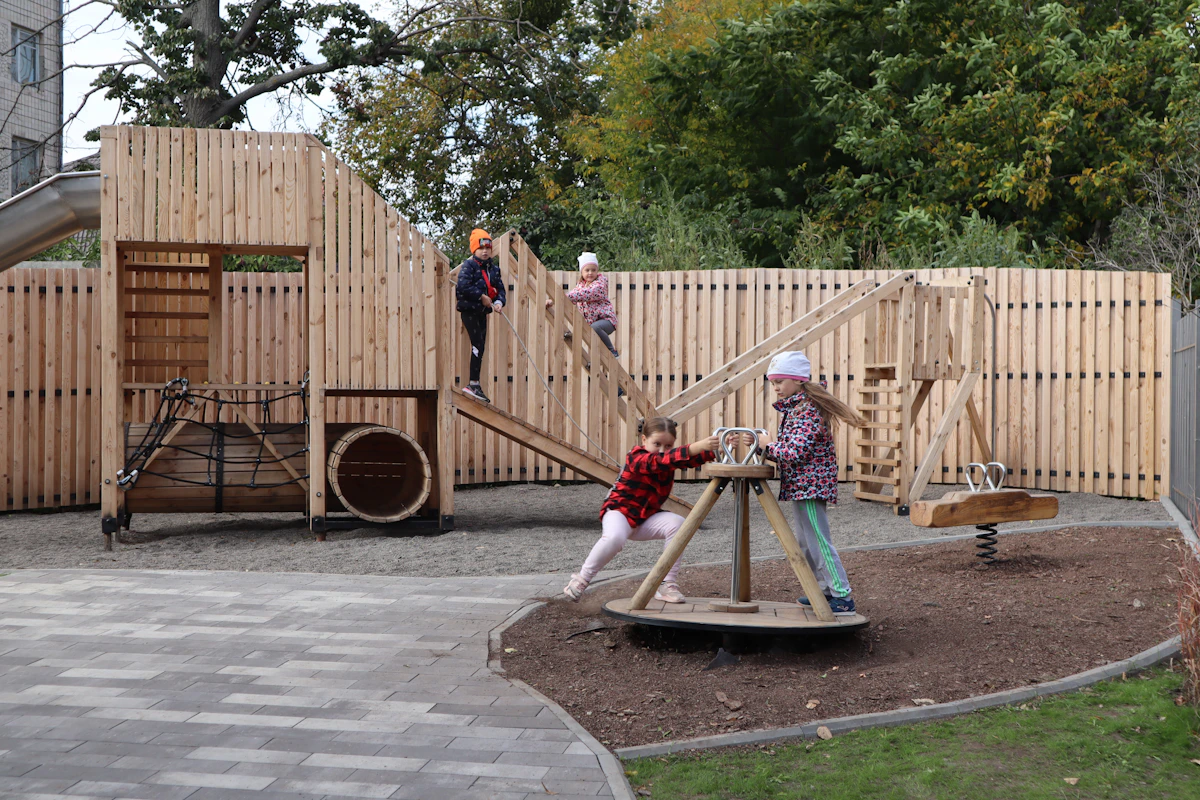 Children playing on a bespoke wooden playground in a leafy park