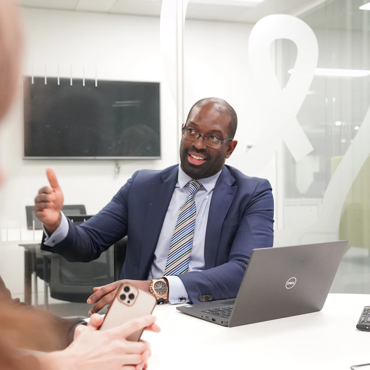 A man in a suit and tie gesturing during a meeting in an office