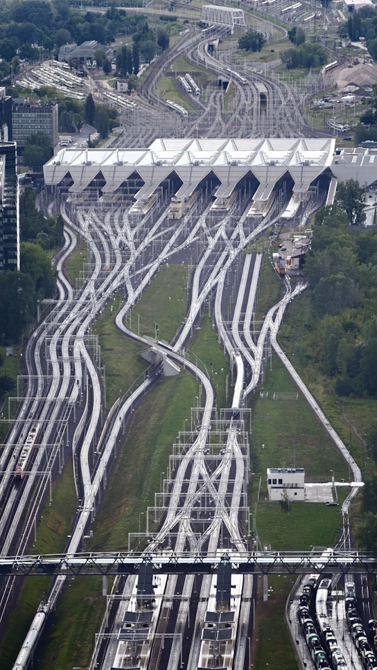 Numerous train tracks lead into a large, modern station building