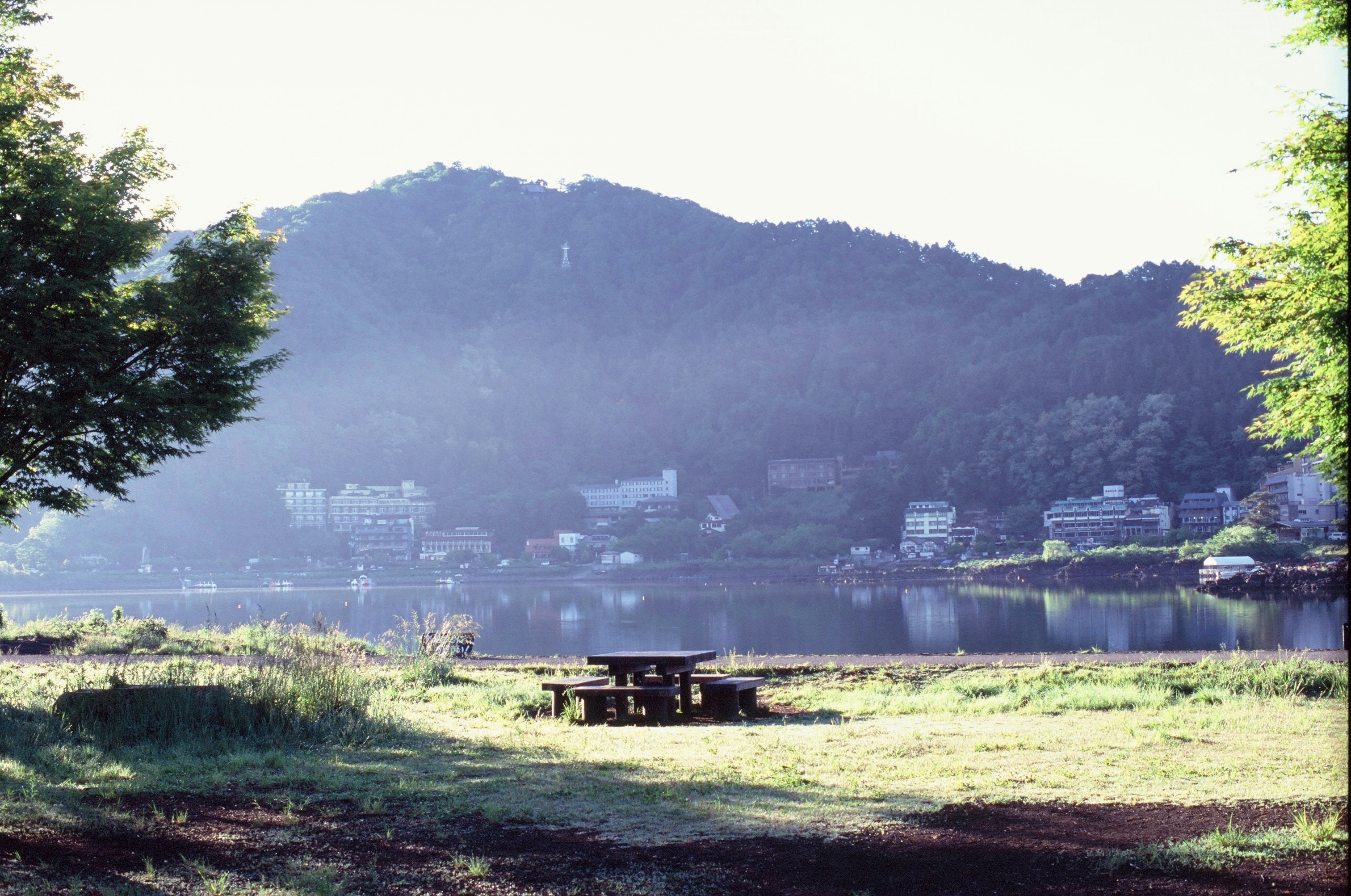 Picnic table by a lake, mountains, and village in background