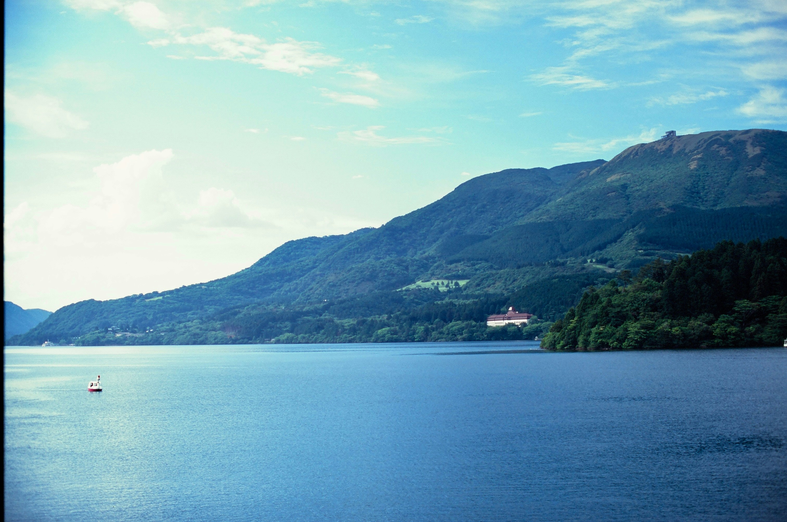 Large blue lake with green mountains and a distant building