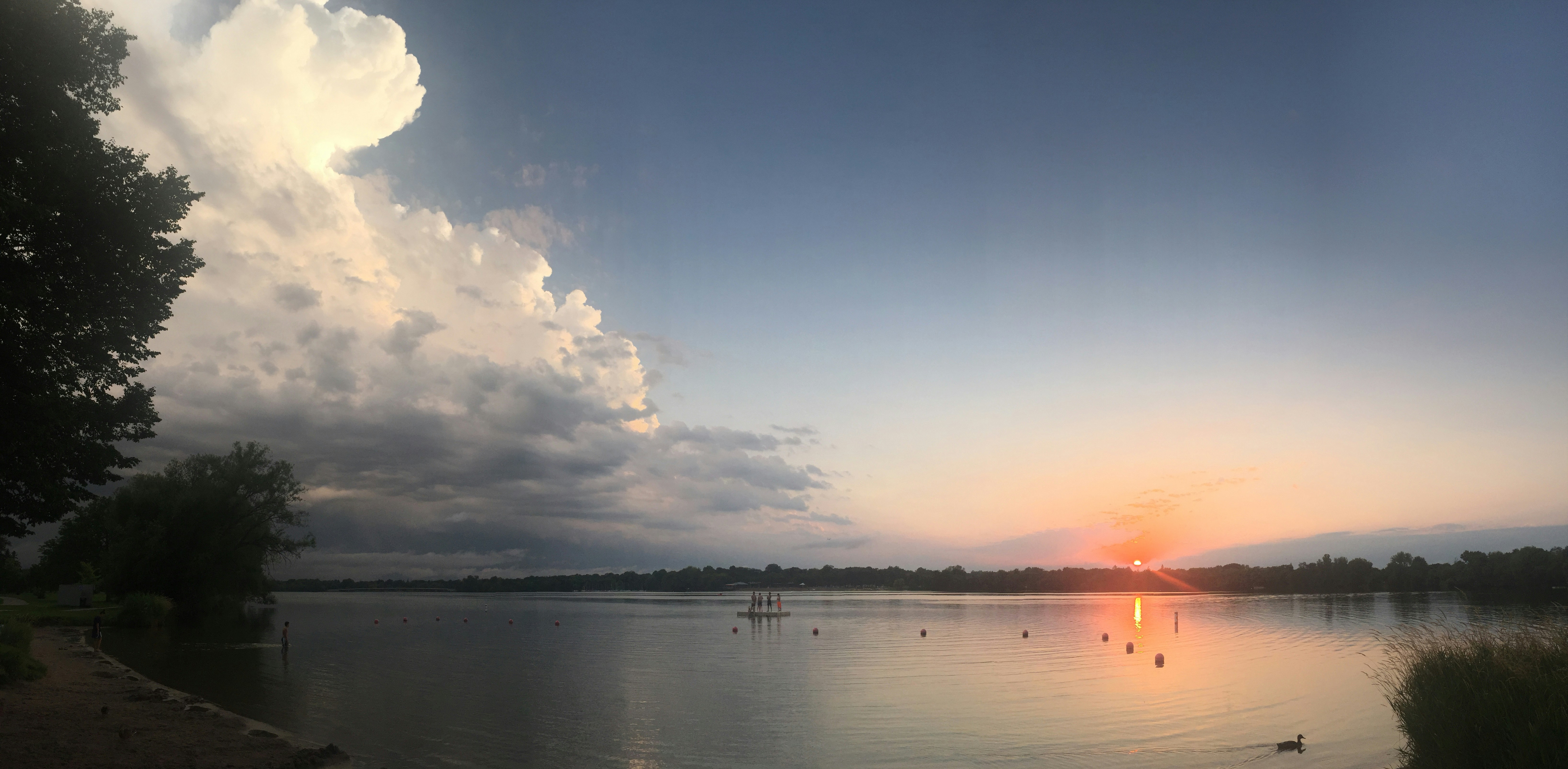 Puesta de sol sobre un lago tranquilo con nubes dramáticas