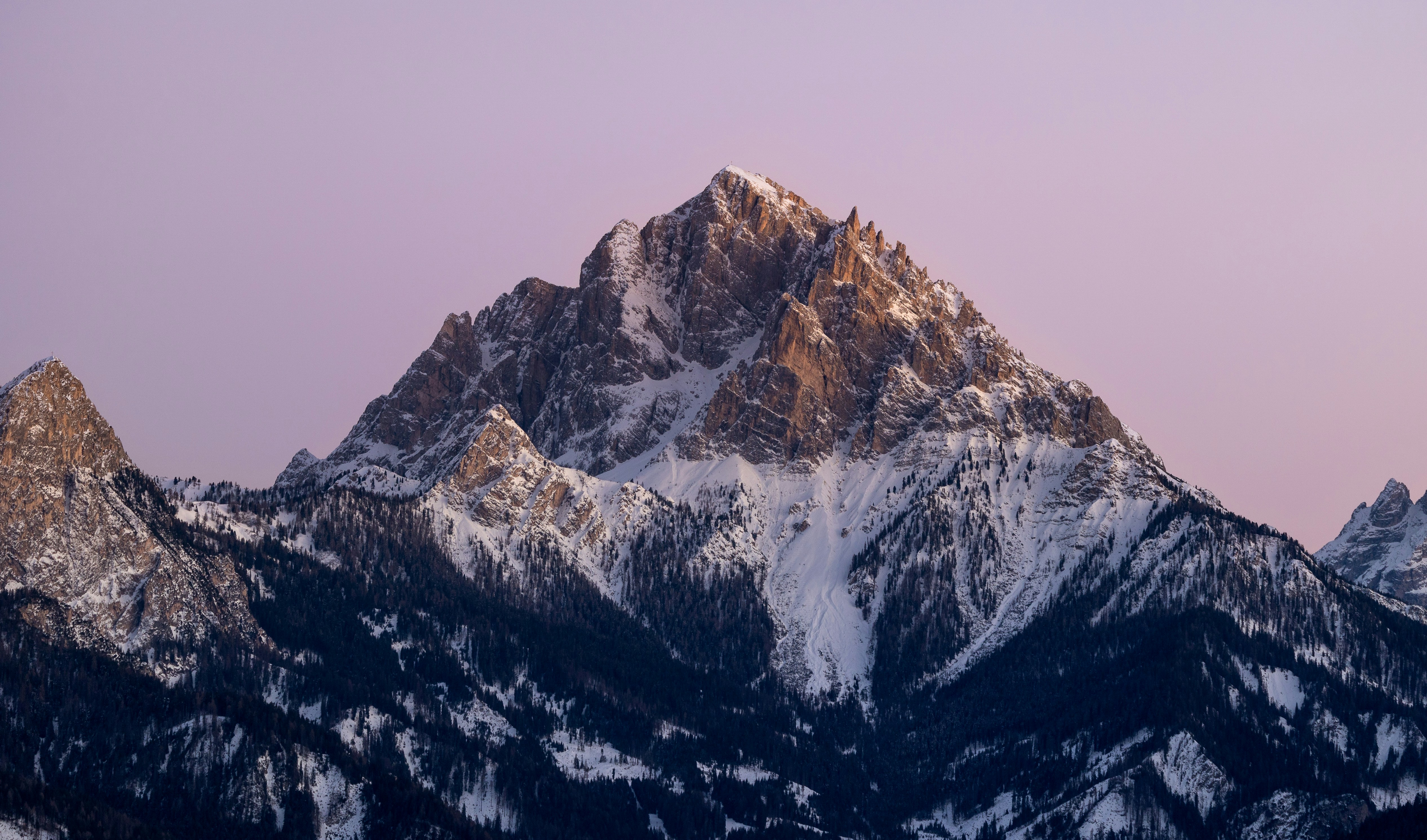 A majestic snow-capped mountain peak under a soft purple sky.