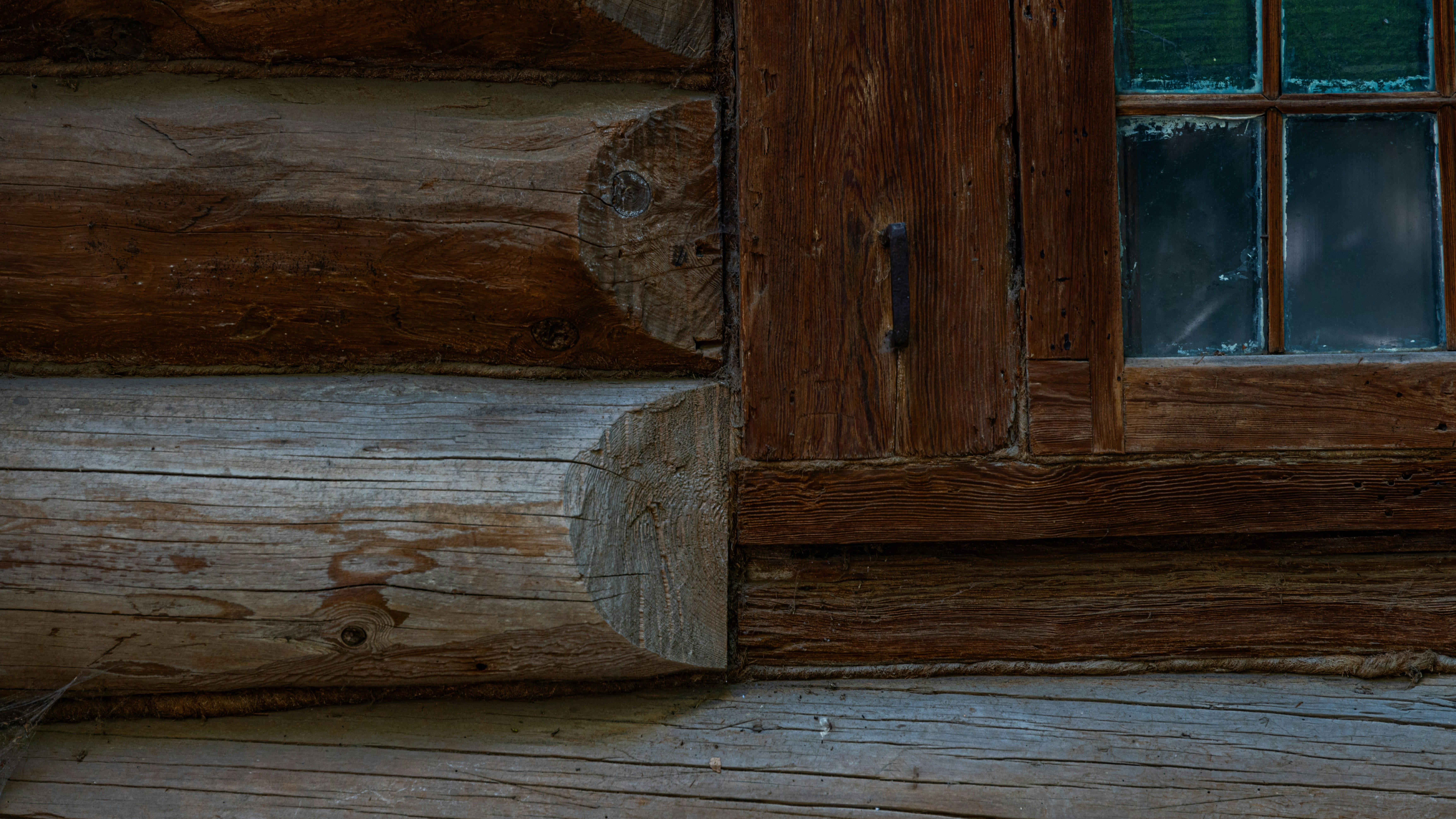 Angolo rustico di una baita in legno con telaio da finestra.