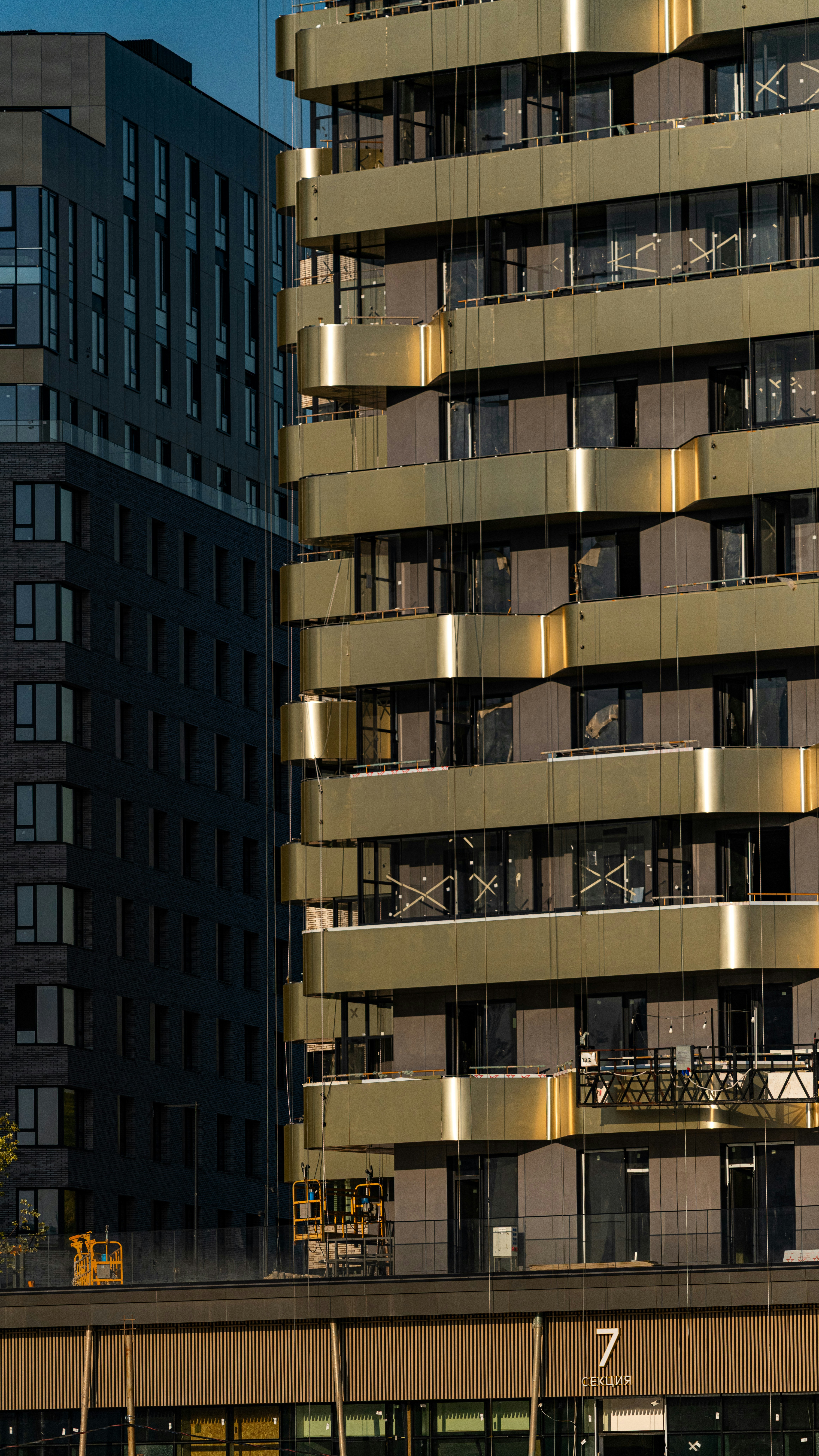 Edifici moderni con facciate scure e dorate in costruzione.