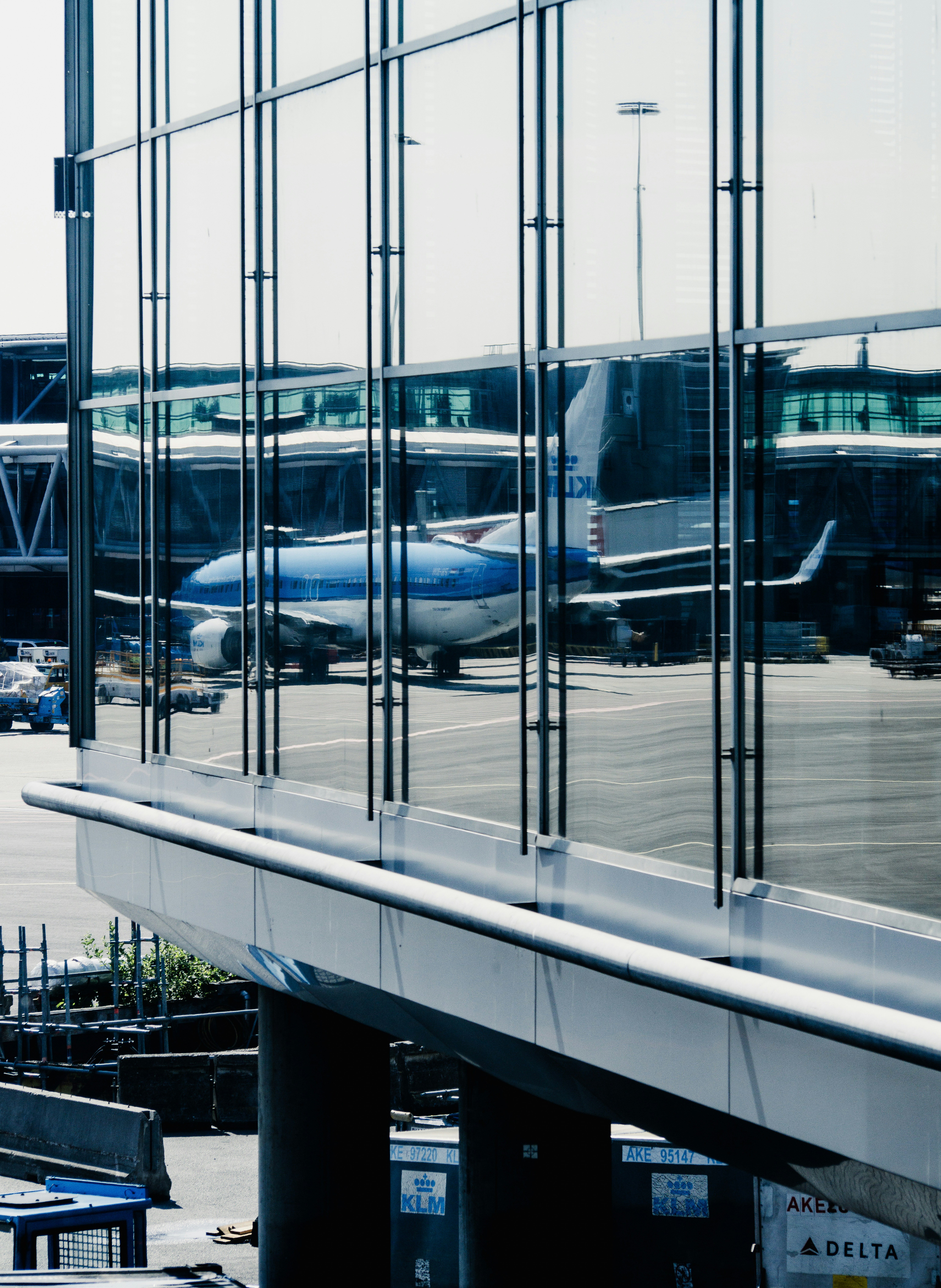 An airplane parked at an airport terminal seen through glass.